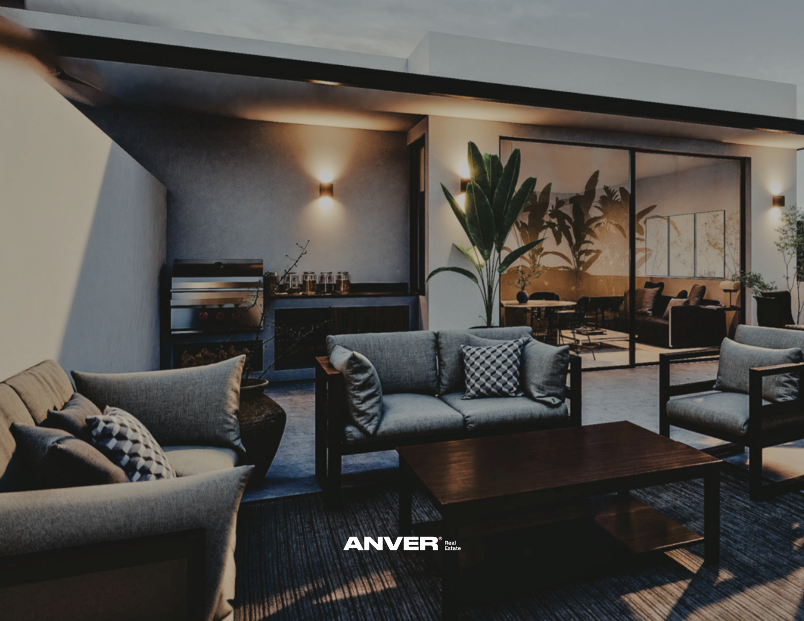 Sala de estar moderna con sillones y mesa de centro de madera, planta grande, iluminación suave y ambiente acogedor, separada por una pared de vidrio de una segunda sala con sillones y mesas.