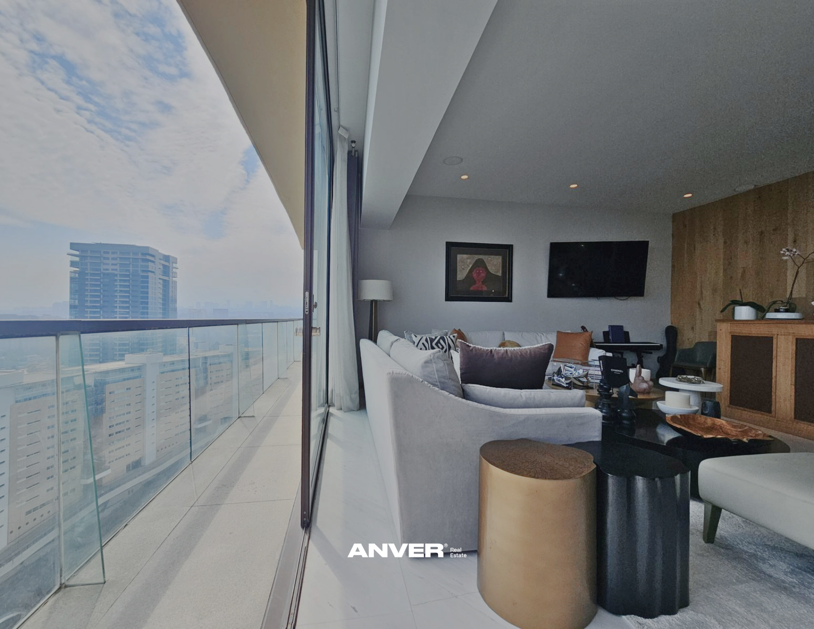 Interior de sala de estar en un apartamento de lujo con balcón y vista a la ciudad, mobiliario moderno y decoración elegante.