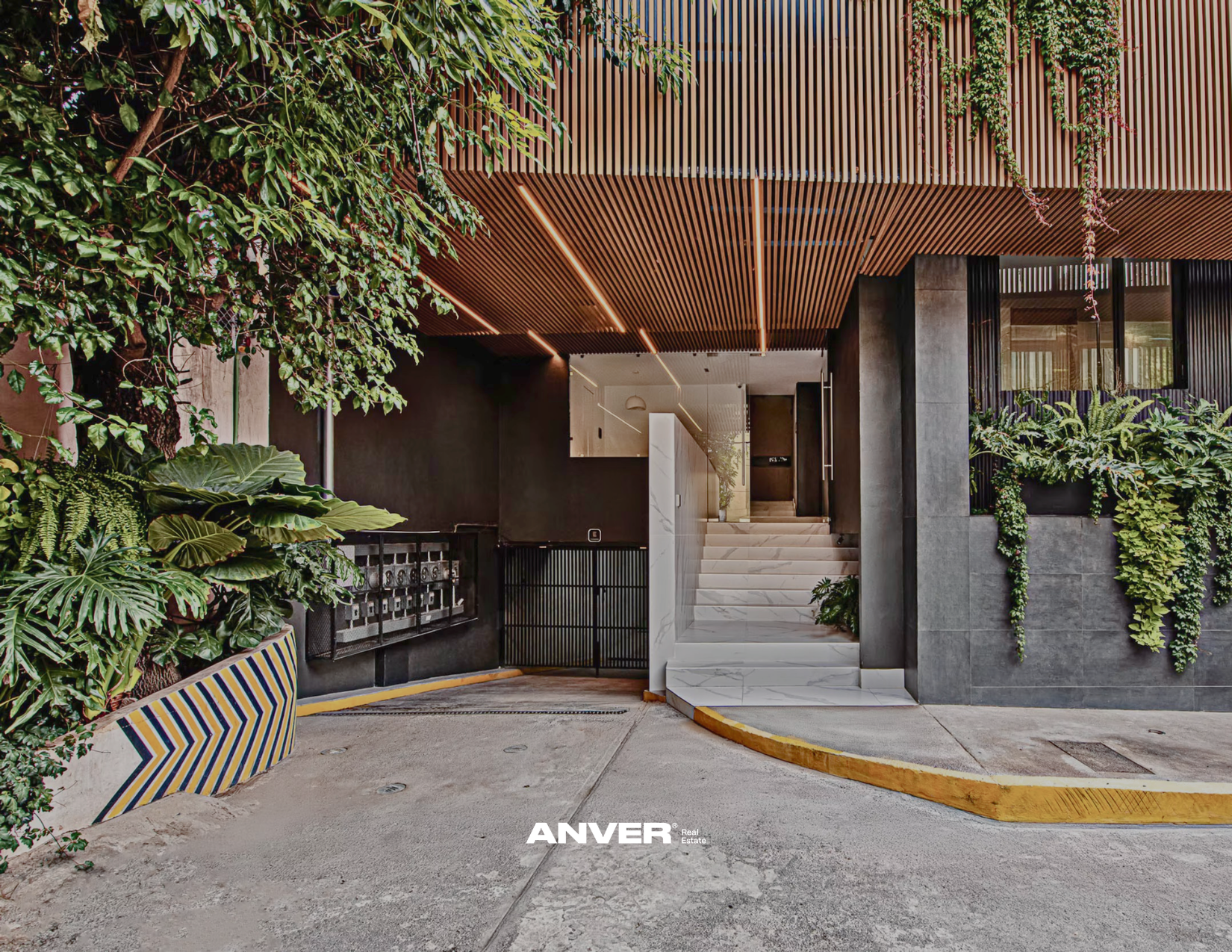 Entrada moderna a un edificio con vegetación decorativa en las paredes y techo de listones de madera