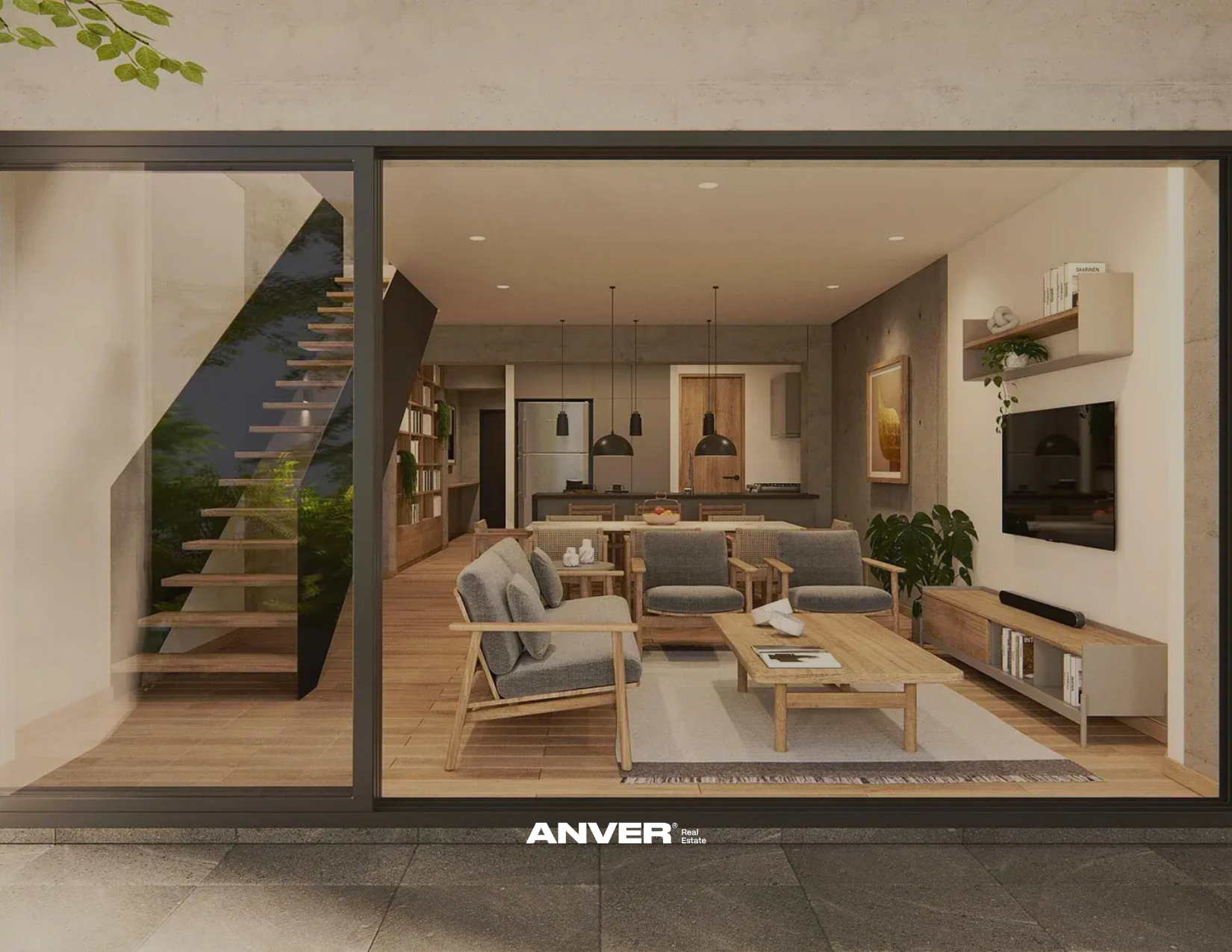 Vista de una sala moderna con sillones de madera y tela gris, mesa de centro de madera con revistas, televisión montada en la pared, estanterías con libros y plantas decorativas, escaleras abiertas de madera y metal, cocina en el fondo con iluminación moderna, paredes de colores neutros, ambiente cálido y acogedor.