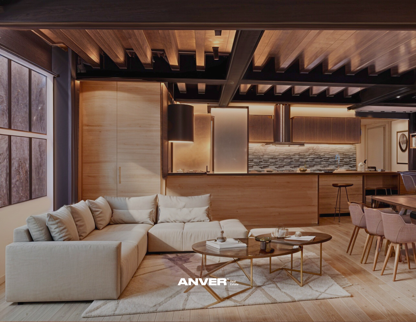 Sala de estar con mobiliario de tonos beige y madera, paredes con cuadros y ventana, en el fondo cocina con barra y paredes de piedra, luminaria cálida y ambiente acogedor