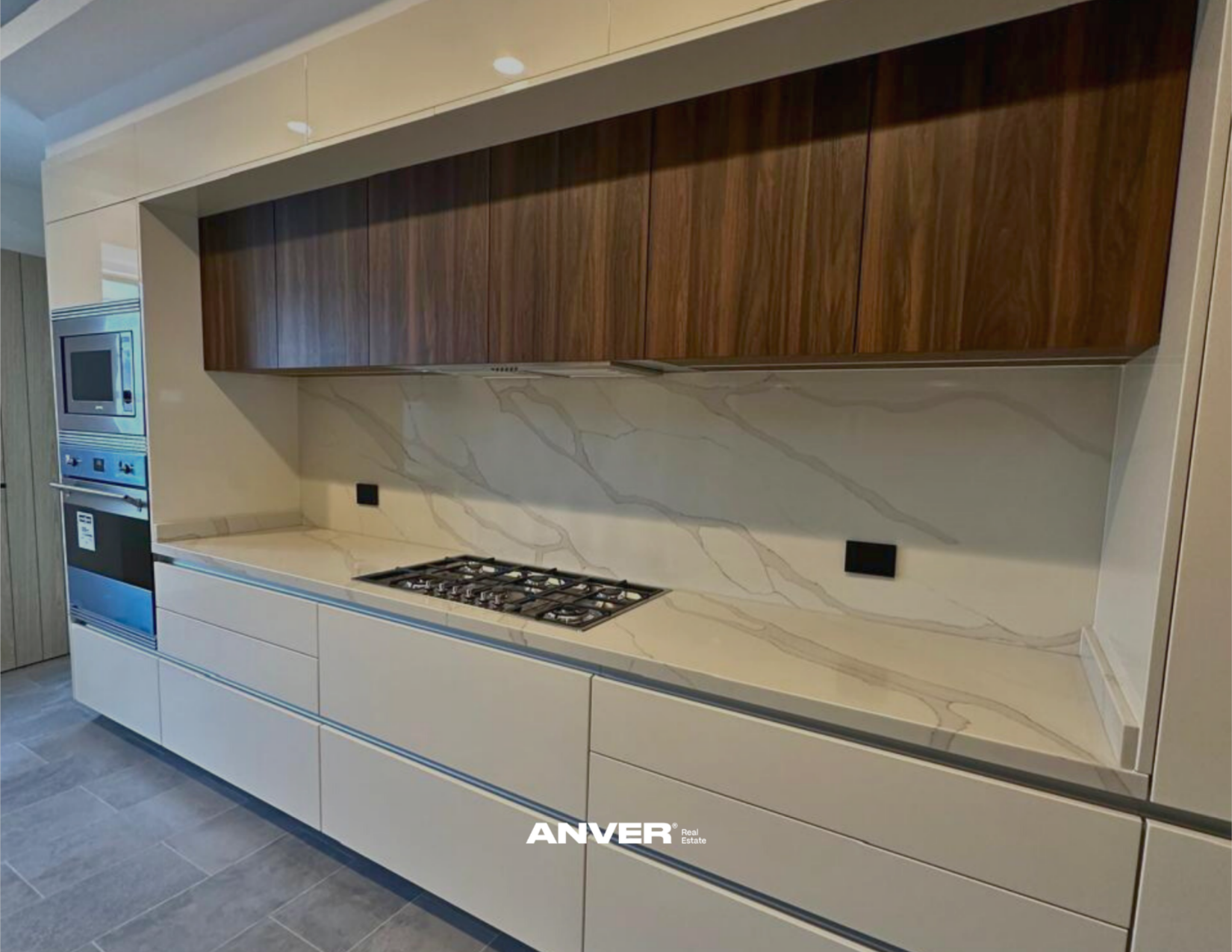Cocina moderna con gabinetes de madera, encimera de piedra y estufa de gas.