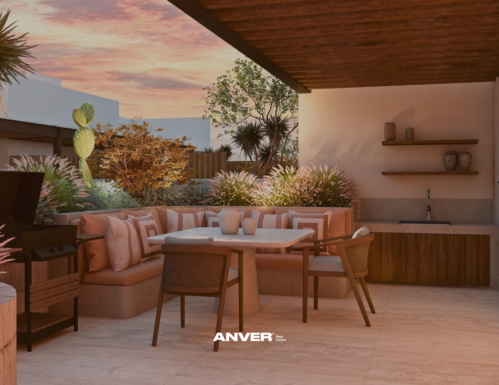 Terraza moderna con vista a la puesta del sol, zona de descansar con sofá de esquina decorado con cojines, mesa redonda con jarrones, área de cocina con lavabo, estantes con jarrones y plantas, y vegetación en el fondo.