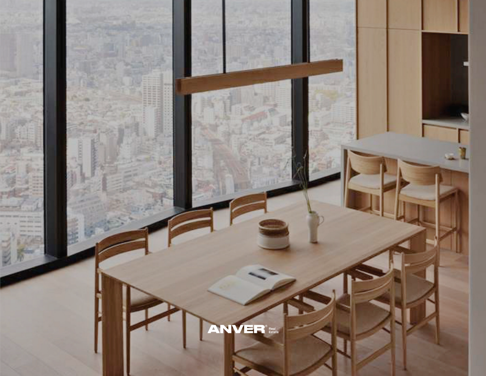 Interiores de una sala de reuniones con mesa de madera y sillas, vista de la ciudad a través de ventanas grandes de piso a techo.
