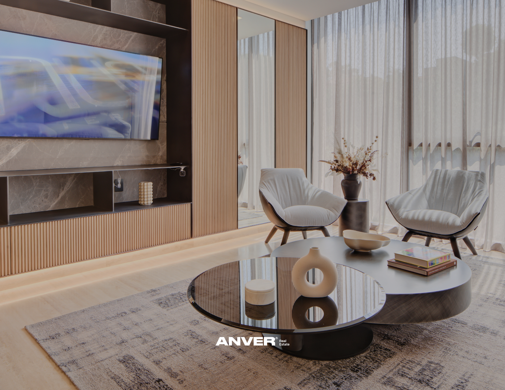 Sala moderna con sillones blancos, mesa de centro negra, cortinas translucidas y un mueble con televisión. Elementos decorativos como cerámicas y libros