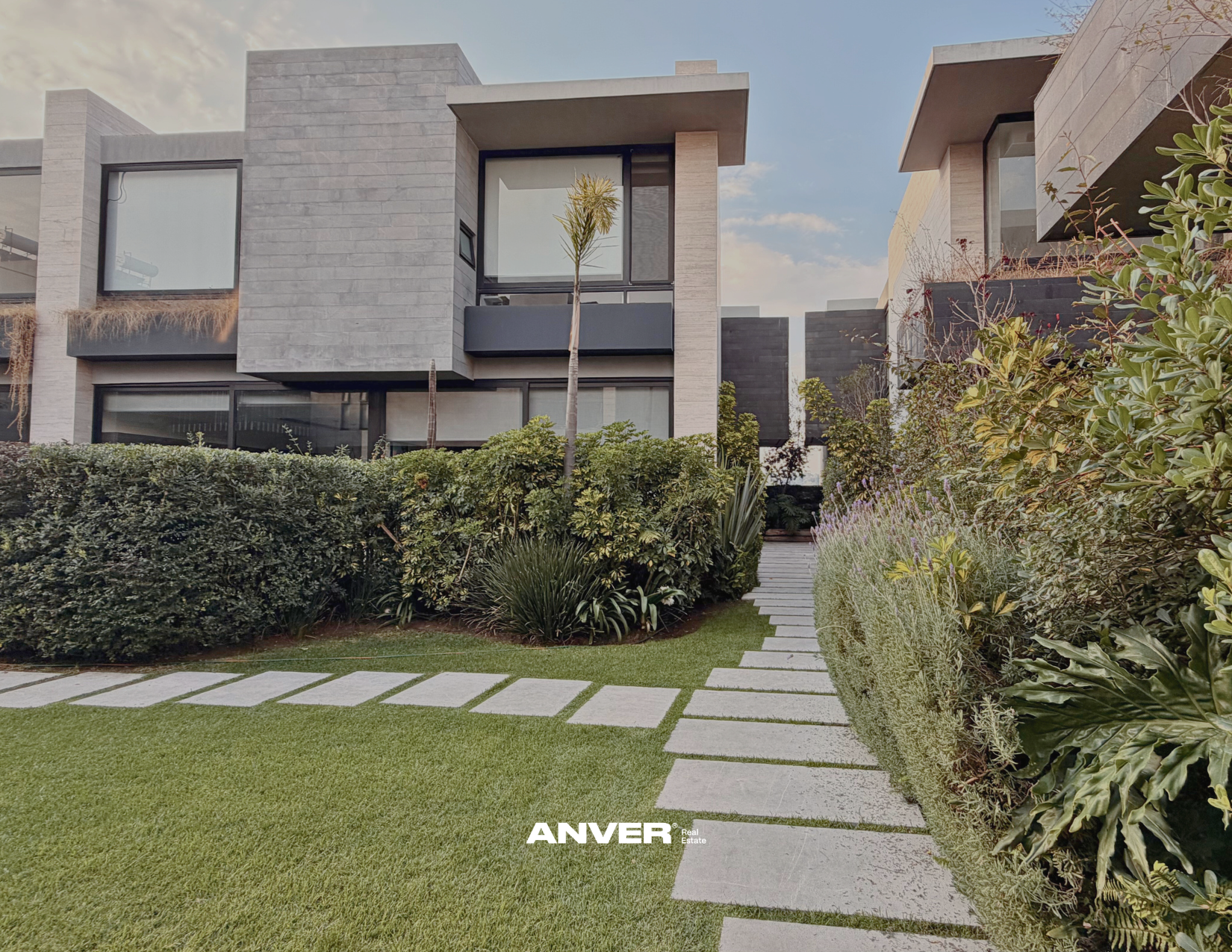 Vista de casas modernas con jardín y caminos de piedra. 