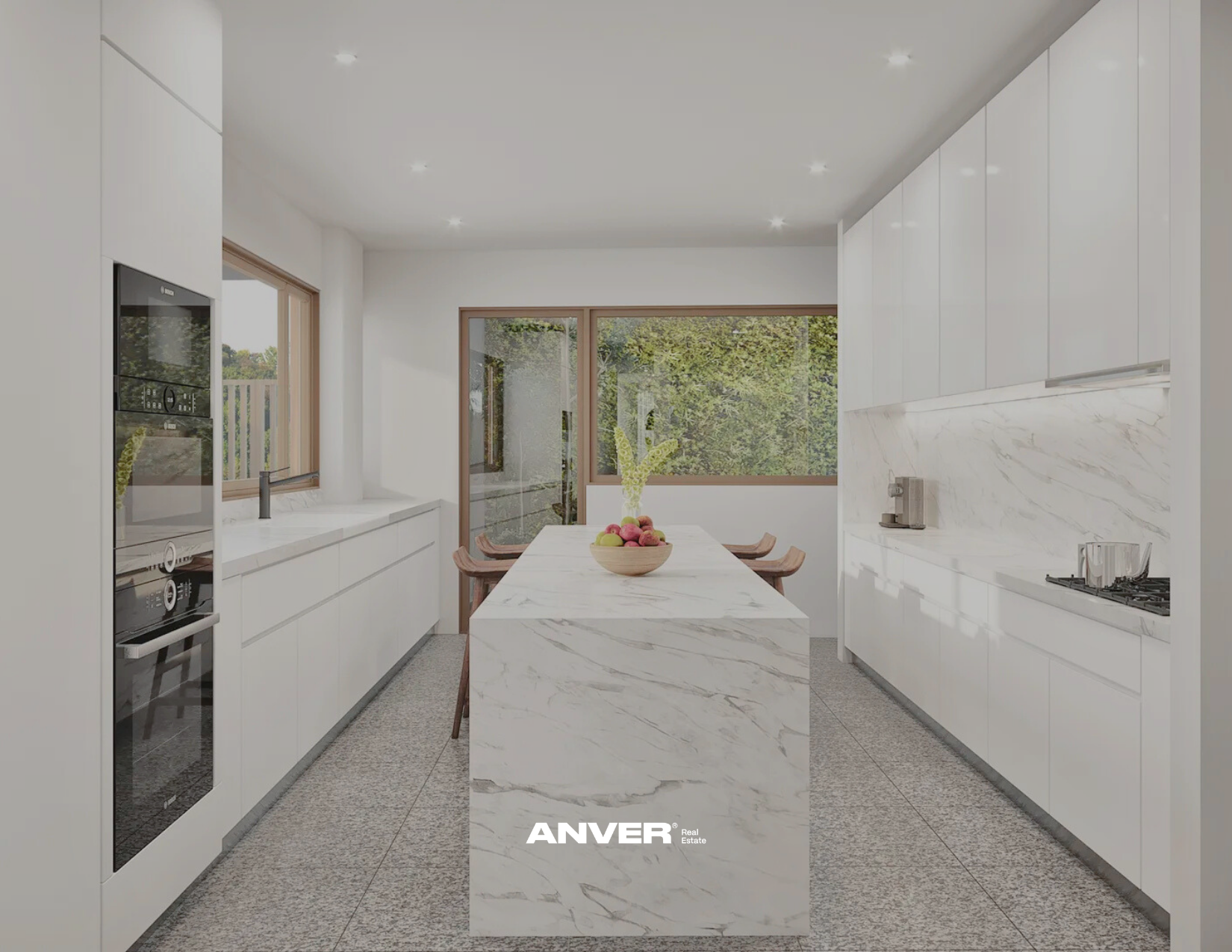 Cocina moderna blanca con isla y vista a ventanas con árboles, mesa con fruta y sillas de madera.