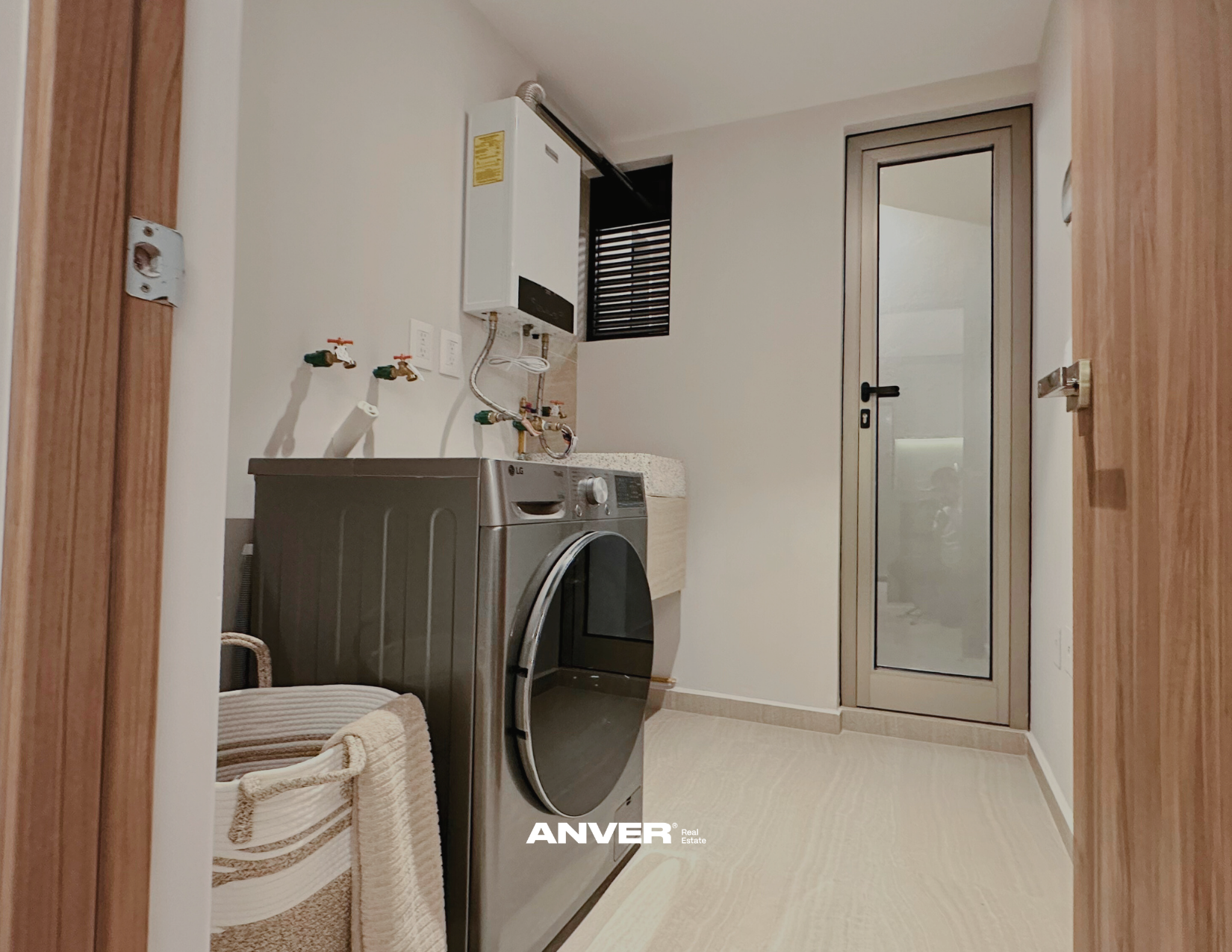 Lavandería con lavadora, calentador de agua, lavabo, ventanas y puerta de vidrio.