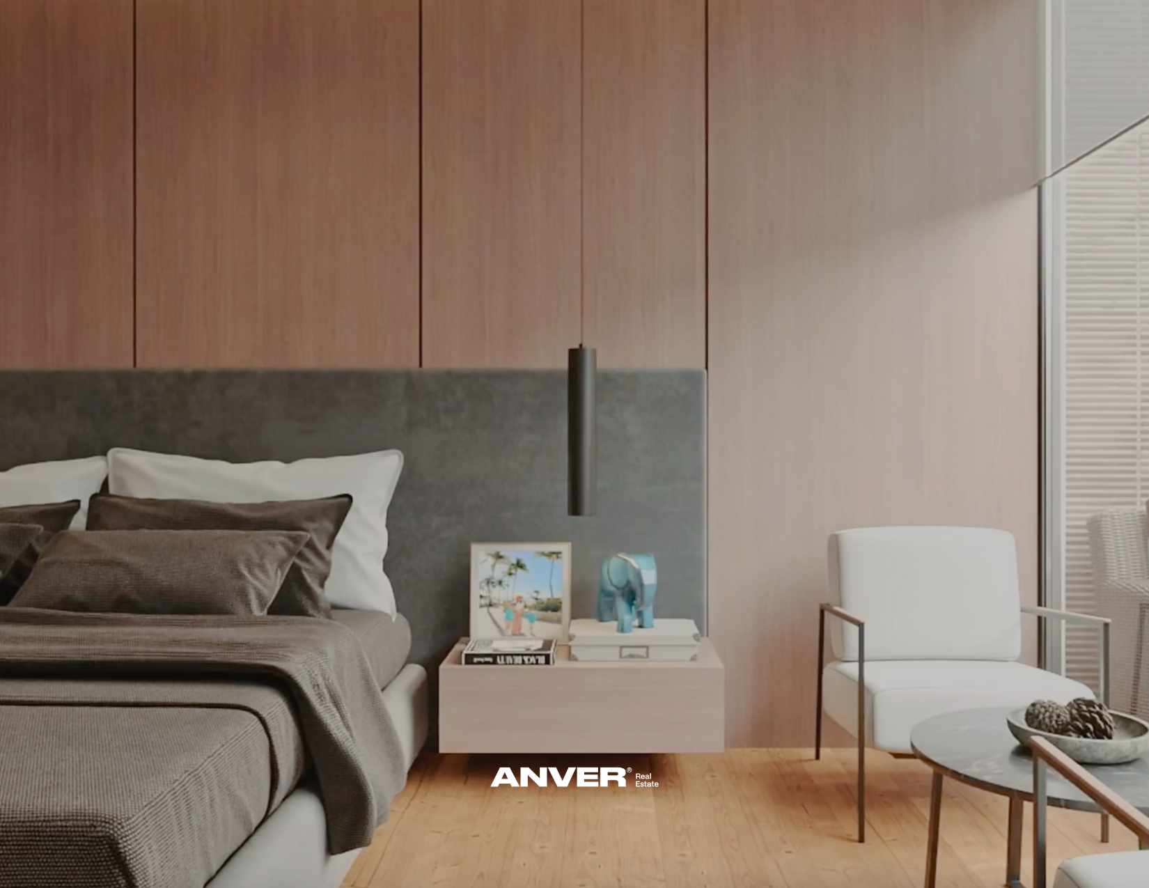 Habitación moderna con cama, almohadas, mesita con fotos y decoración, sillón blanco, mesa de centro con objetos decorativos, madera en pared y suelo, ventana con persianas.