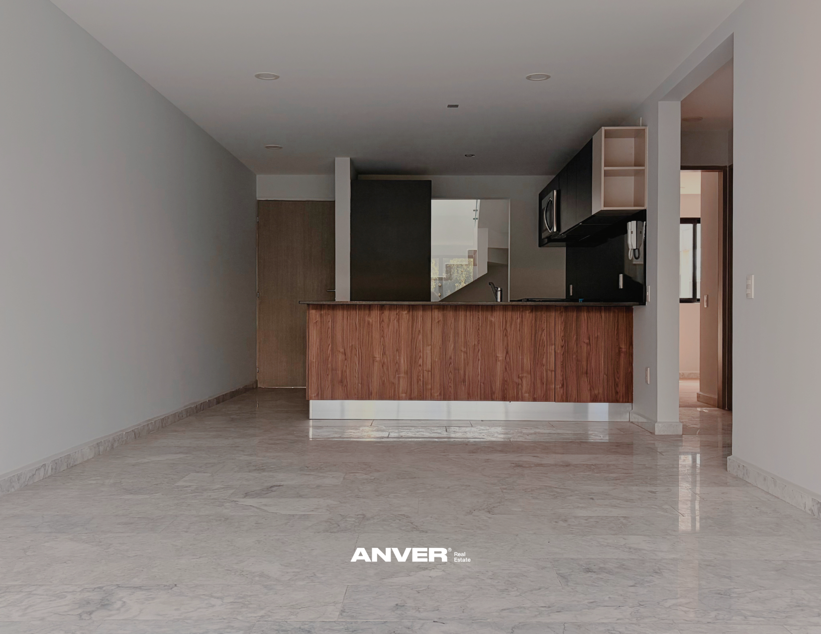 Espacio vació con cocina moderna y suelo de mármol claro.