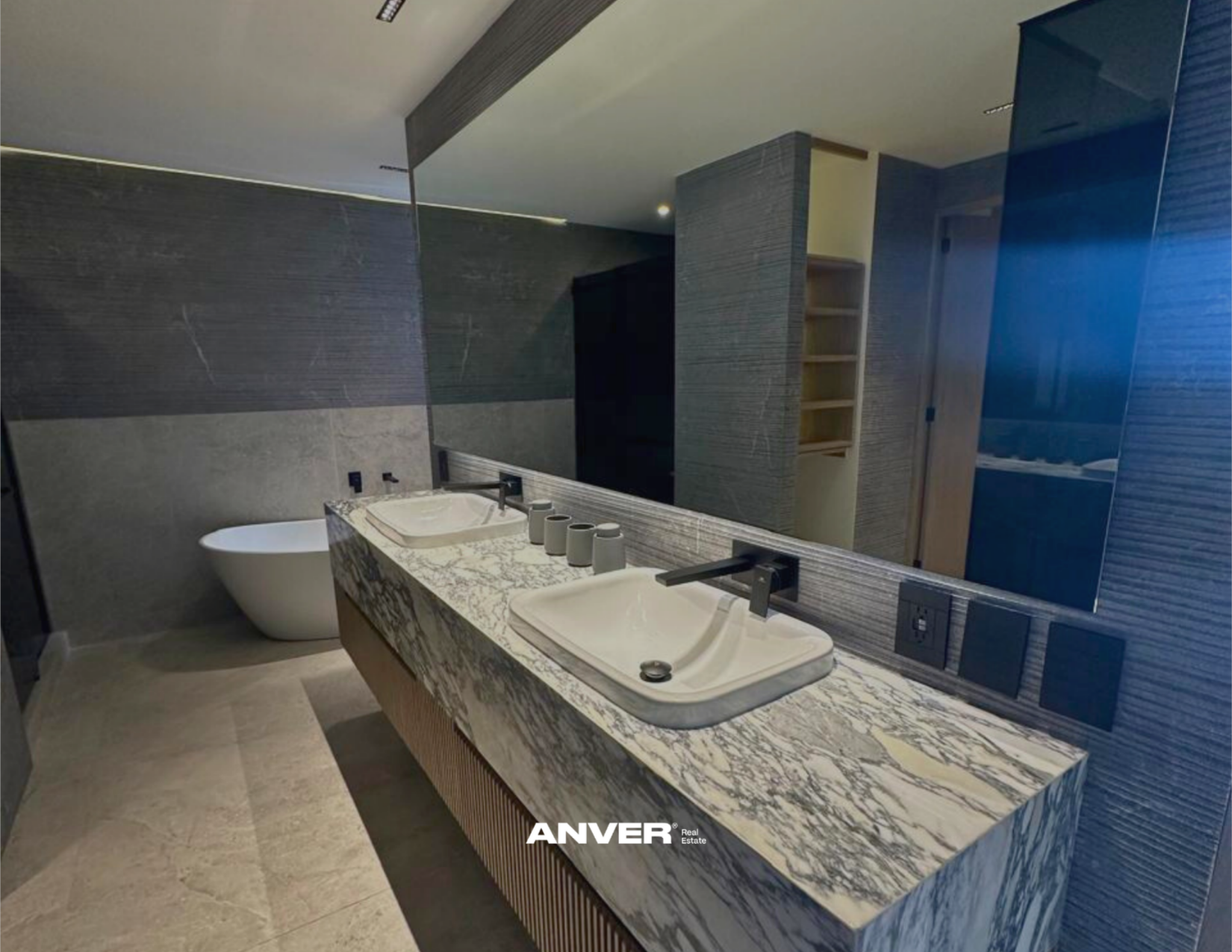 Lavabo doble con encimera de granito y accesorios en el baño, espejo grande, bañera y paredes de piedra moderna.