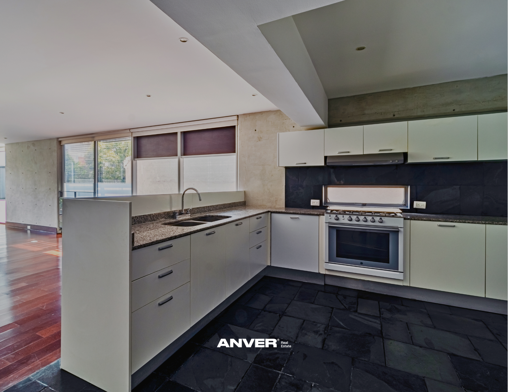 Cocina moderna con gabinetes blancos, estufa, horno y una ventana pequeña que entra luz natural.