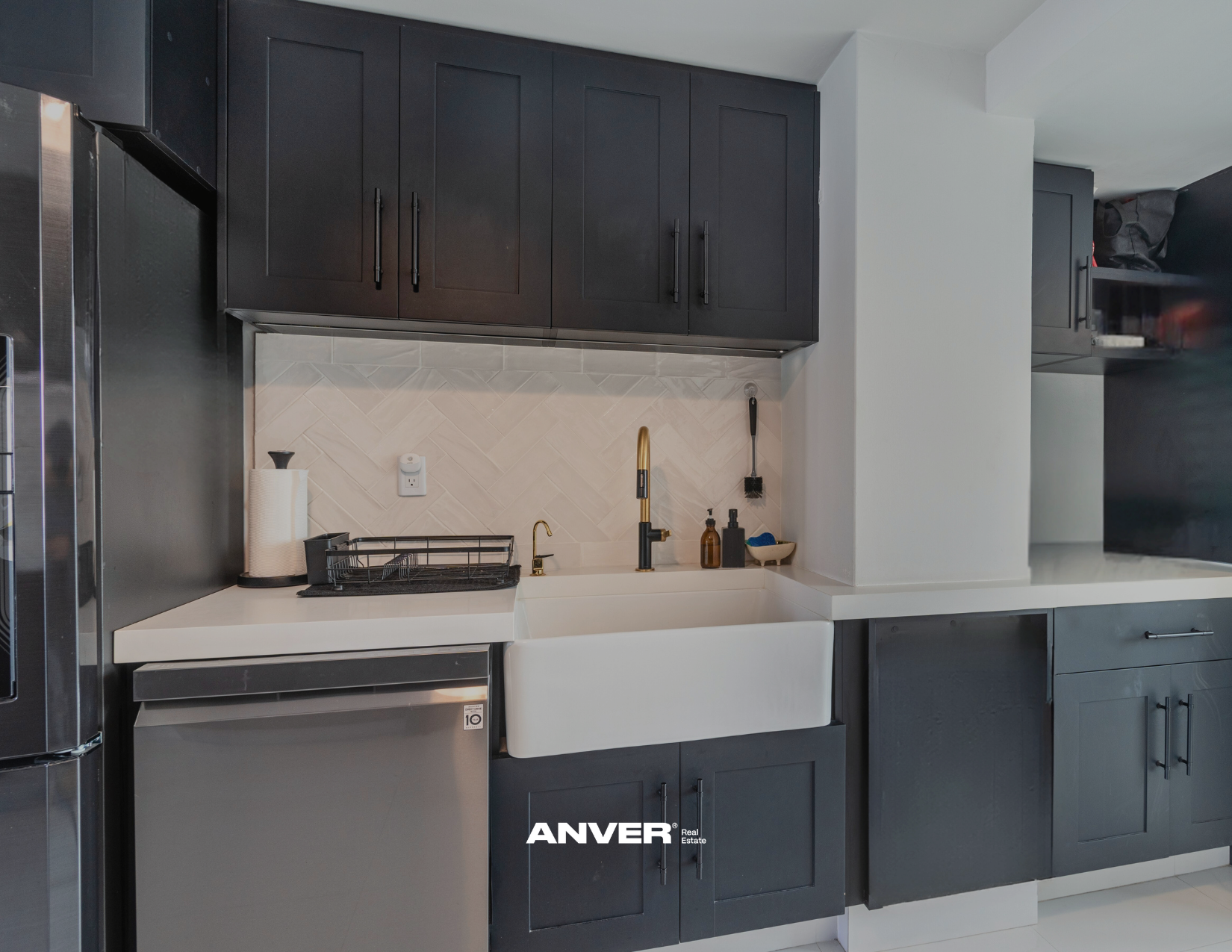 Cocina moderna con gabinetes negros, fregadero con lavavajillas, y utensilios de cocina.