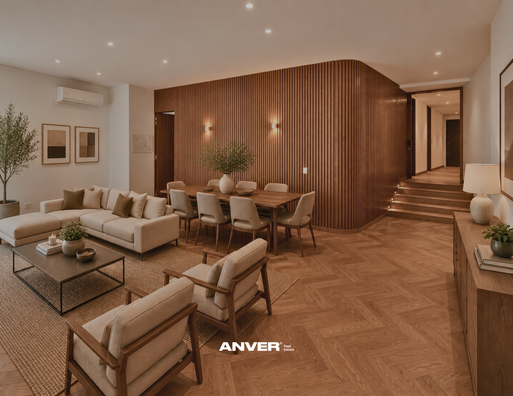 Sala de estar con sillones beige, mesa de café, plantas, una pared de madera y una escalera.