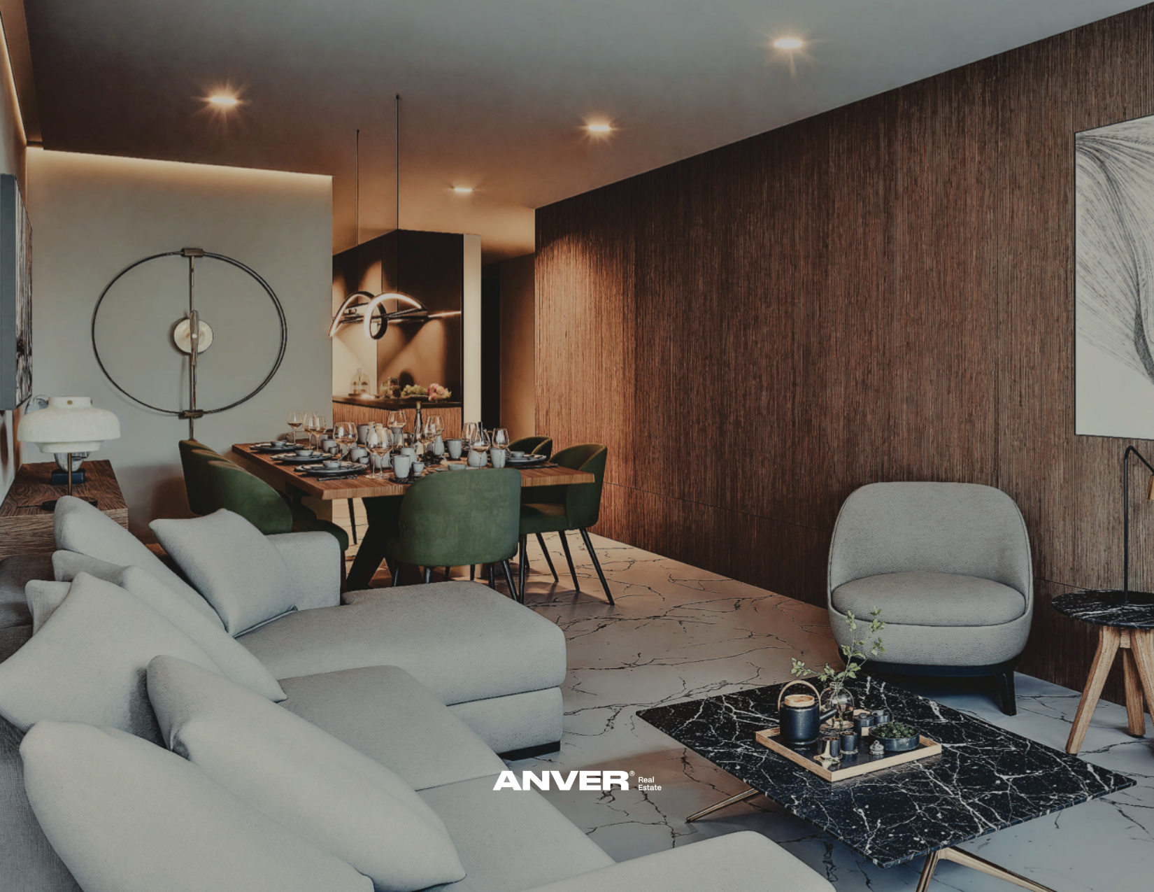 Sala moderna y elegante con sofá gris y mesa de centro de mármol negro, visible en primer plano. En el fondo, área de comedor con mesa de madera rodeada de sillas verdes, y puesta para una comida formal. La decoración incluye un mural abstracto en la pared y un panel de madera oscura que cubre toda la pared trasera. Iluminación tenue con focos en el techo.