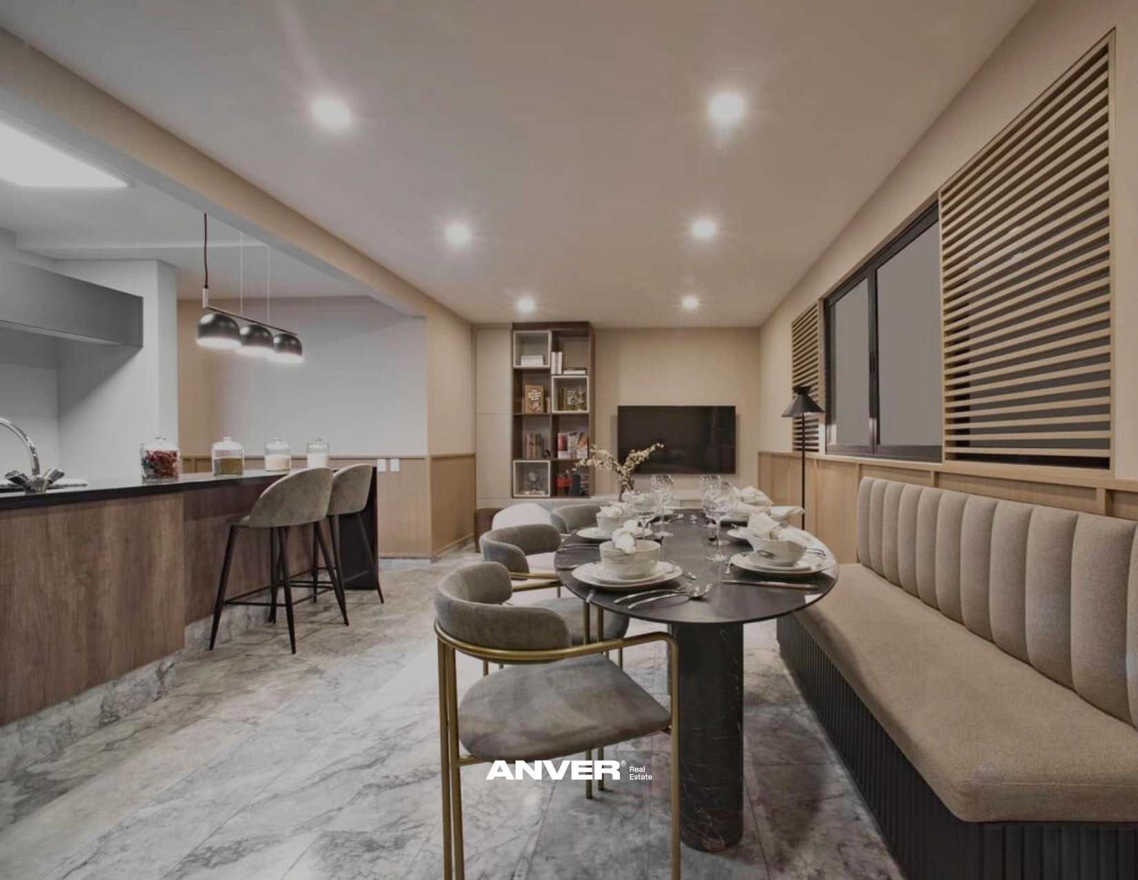 Sala de cena moderna con mesa adornada, sillas y un sofá beige. Cocina en el fondo con barra y taburetes, lámparas y ventanas al lado derecho con persianas.