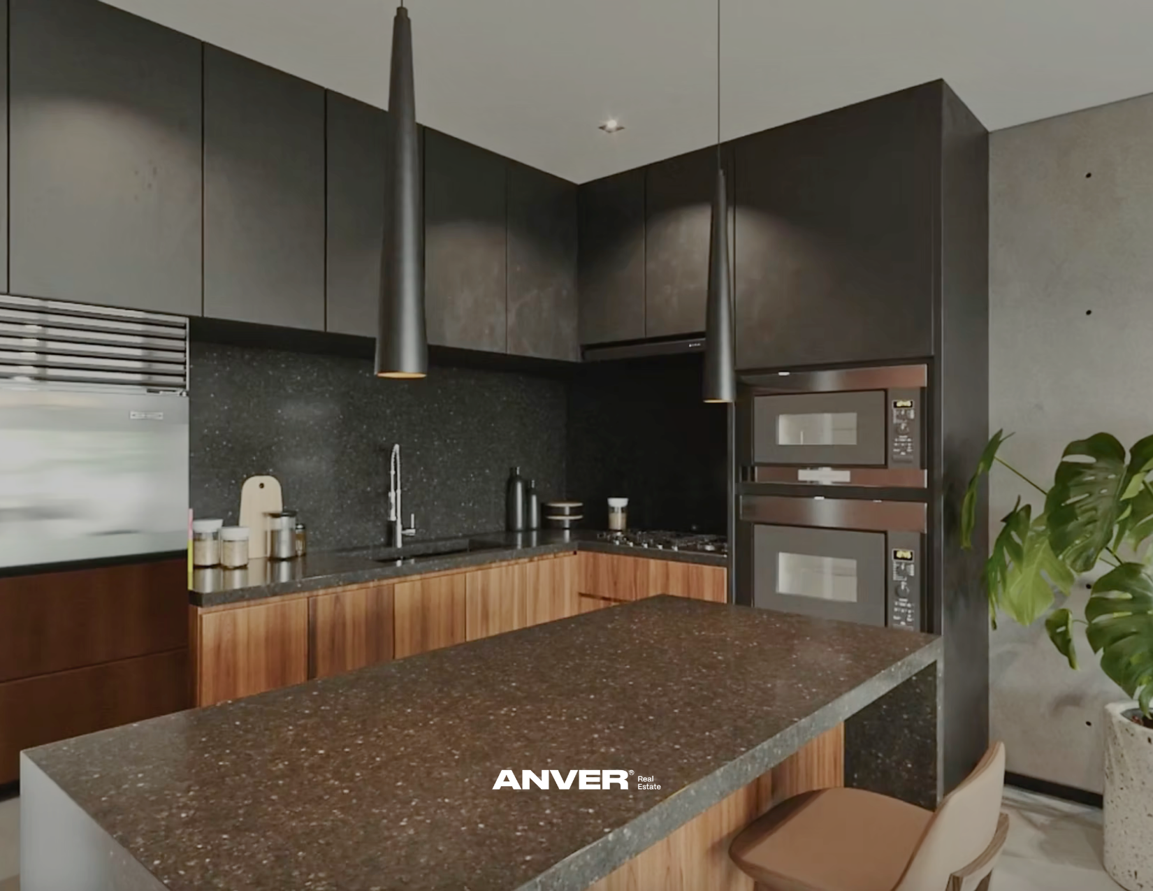 Cocina moderna con campana extractora, gabinetes oscuros y una isla con encimera de granito. Incluye electrodomésticos empotrados, una planta y utensilios de cocina.