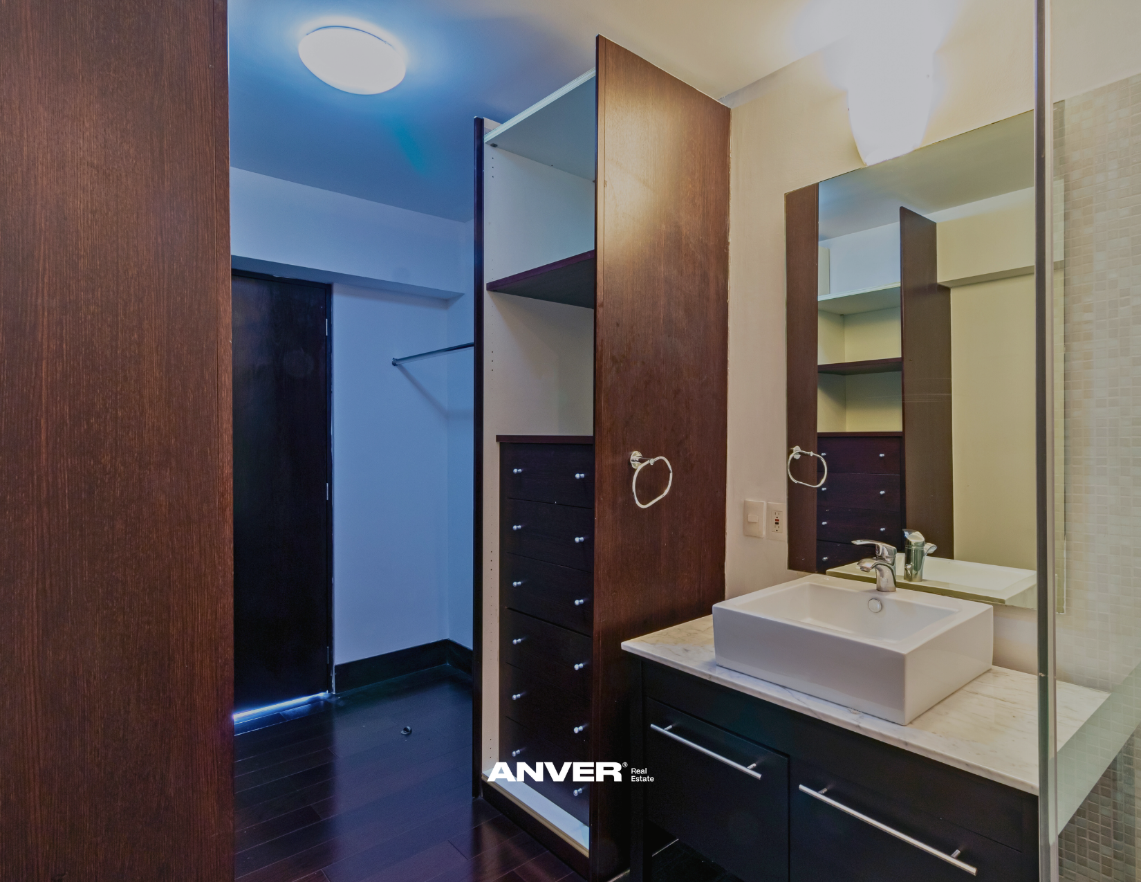 Imagen de un baño con un lavabo, espejo grande, gabinetes de madera y una pared con mosaico