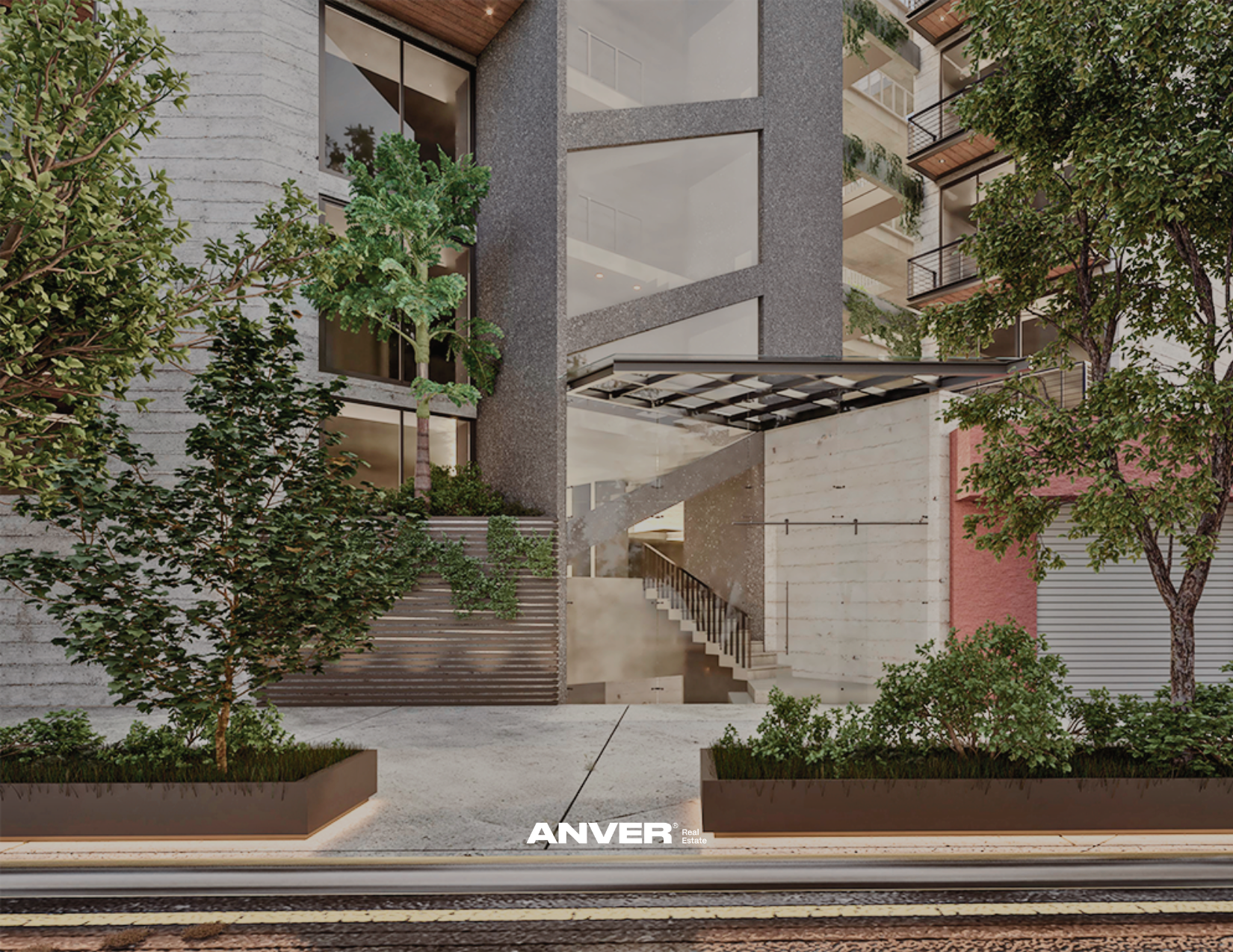 Edificio moderno con varias plantas y balcones, rodeado de árboles y plantas en macetas, con entrada principal por escaleras y vías del tren en primer plano.