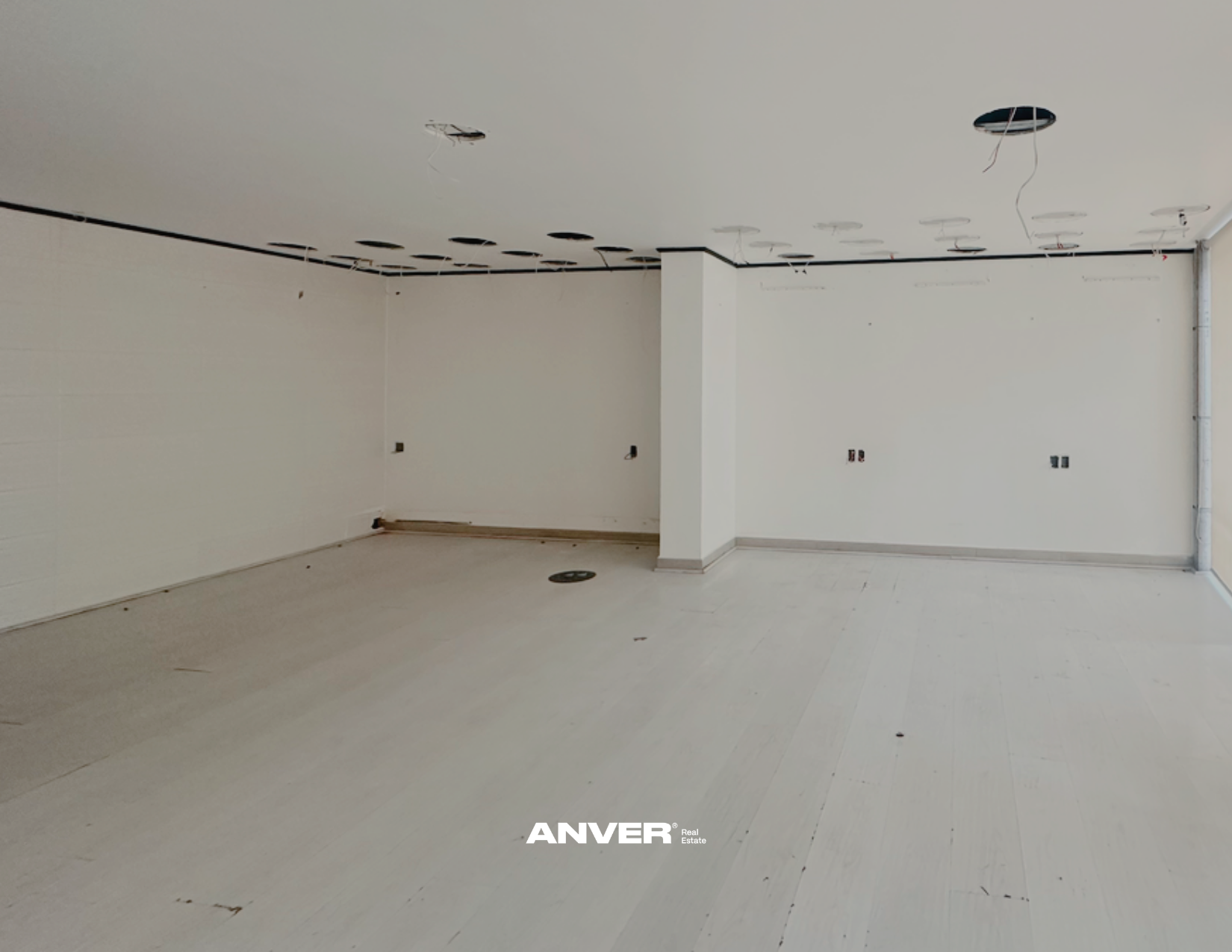 Interior en construcción de una habitación con paredes blancas, suelos claros, varias aberturas en el techo y conductos de aire. Sin mobiliario ni decoraciones, lista para acabados.