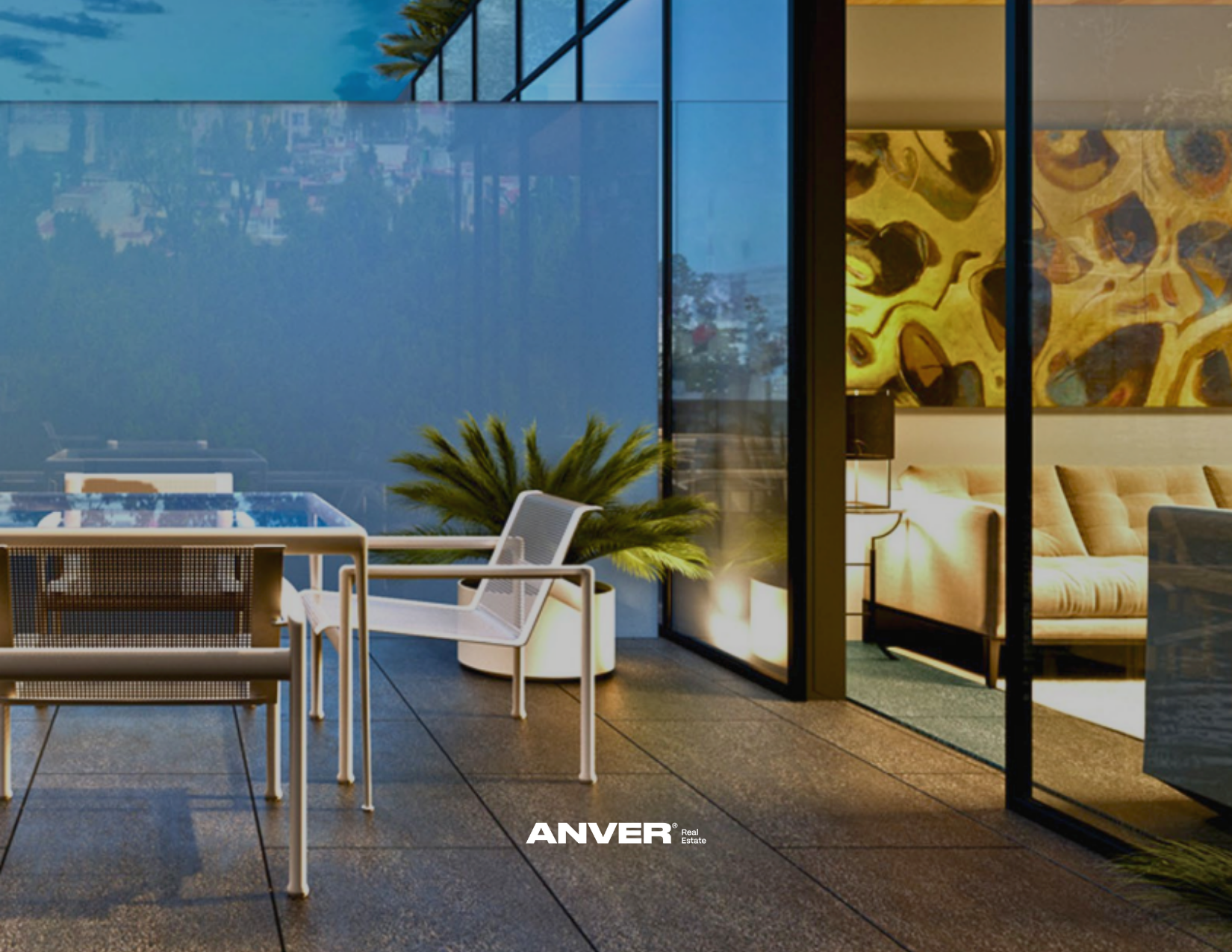 Área de terraza con mobiliario moderno, incluyendo sillas blancas y una mesa, con vistas a la ciudad y plantas decorativas, con interior visible a través de paredes de vidrio, en un ambiente elegante y contemporáneo.