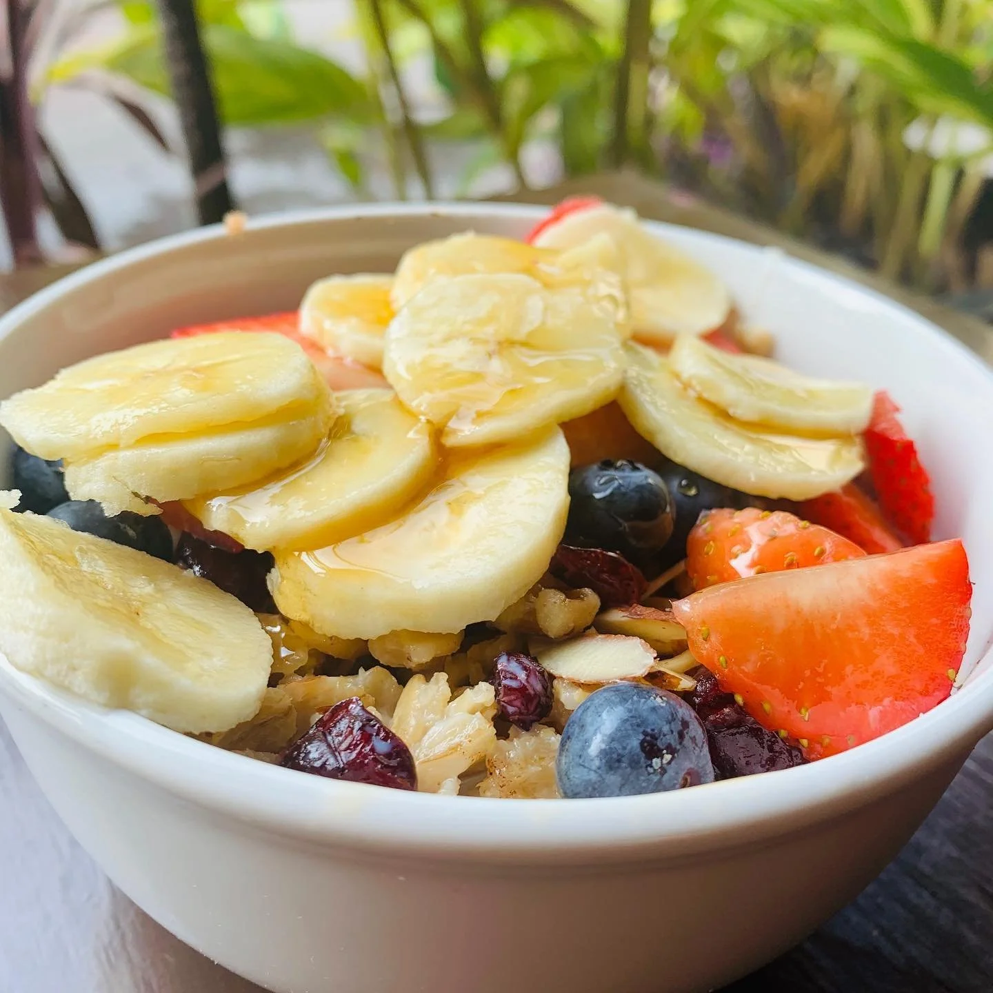 Bowl of mixed fruit including sliced bananas, strawberries, blueberries, and other berries.