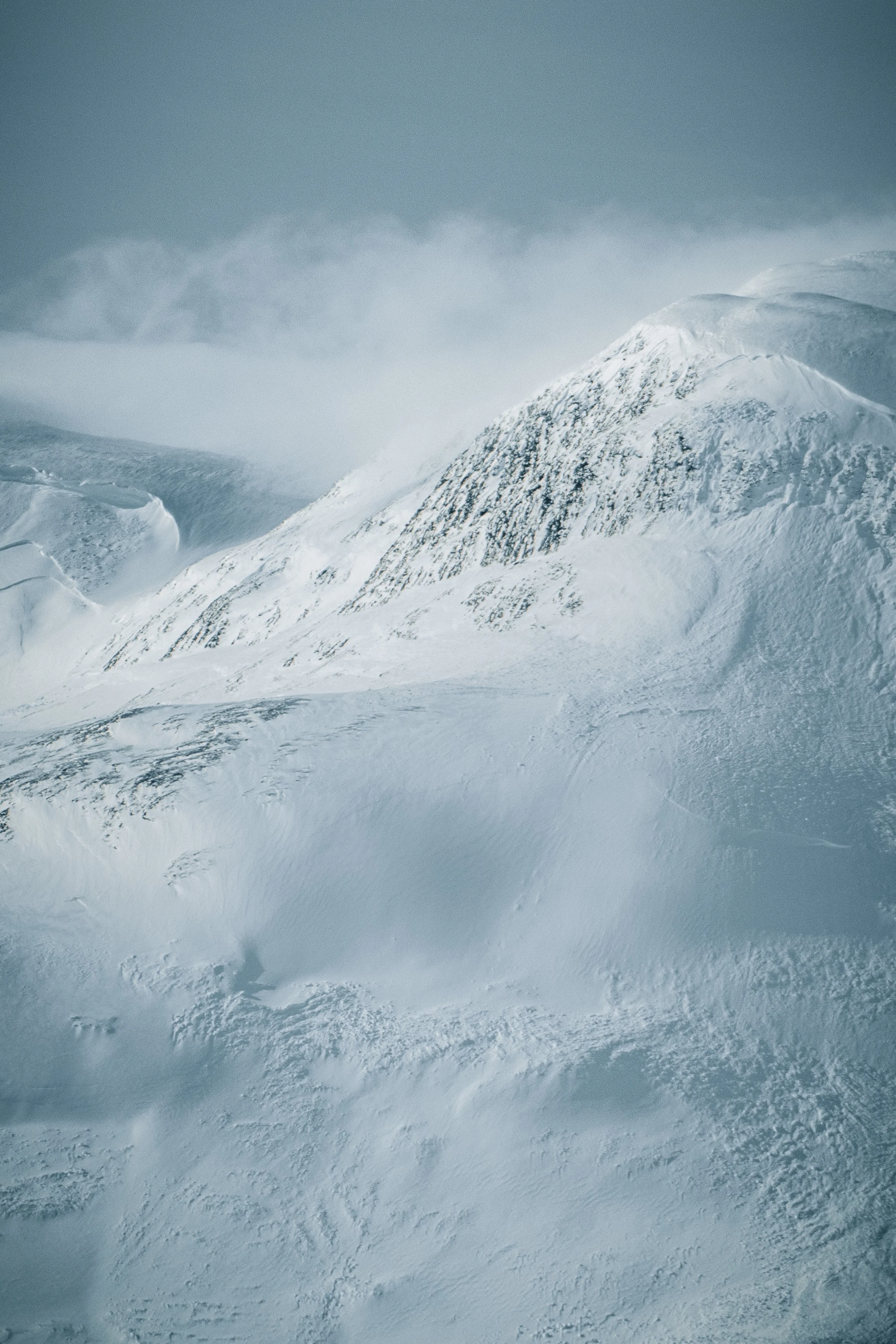 Snow-covered mountain peaks under cloudy sky.