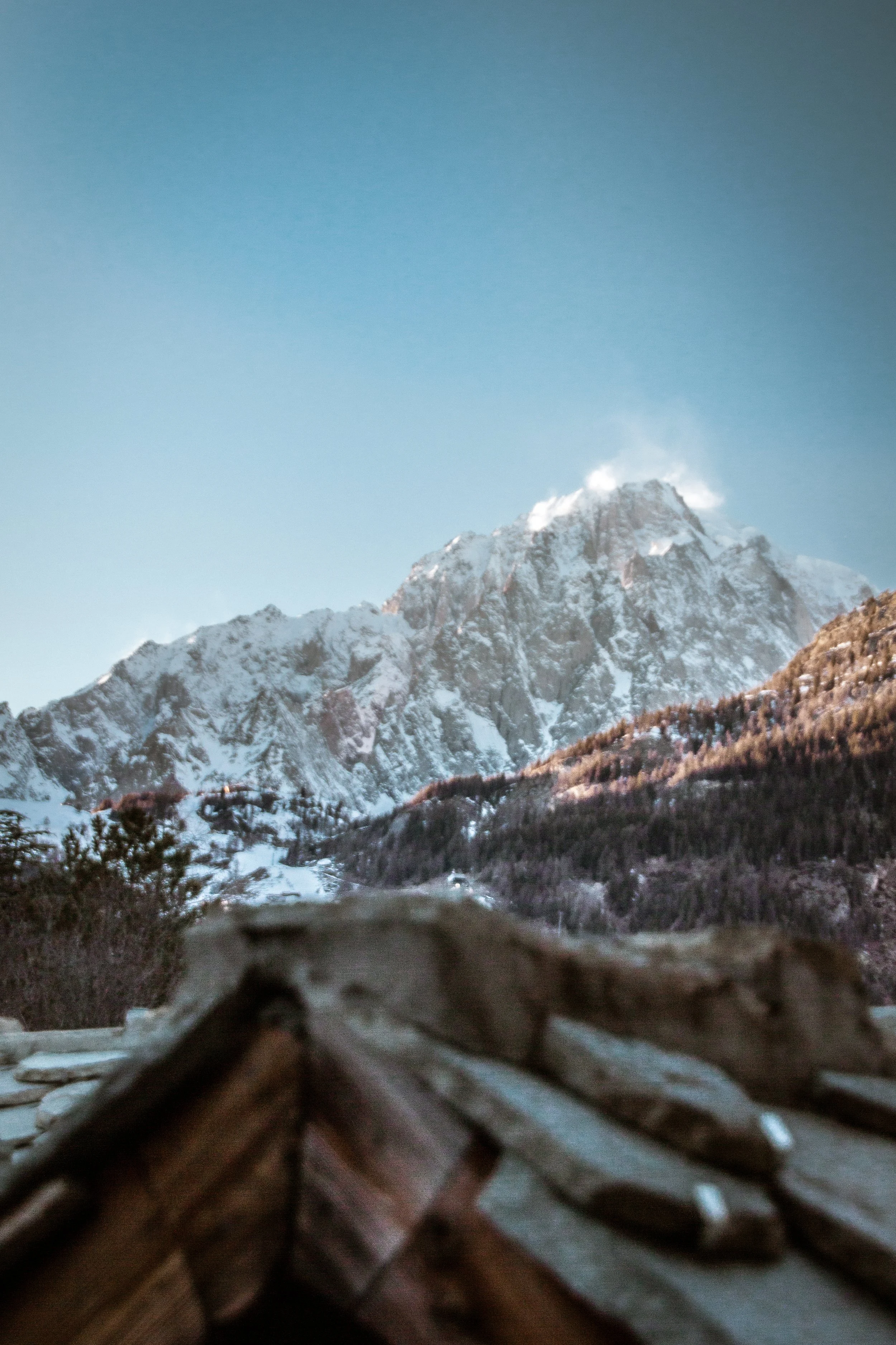 Close-up view of a pile of rocks with blurred mountain and snowy landscape in the background.