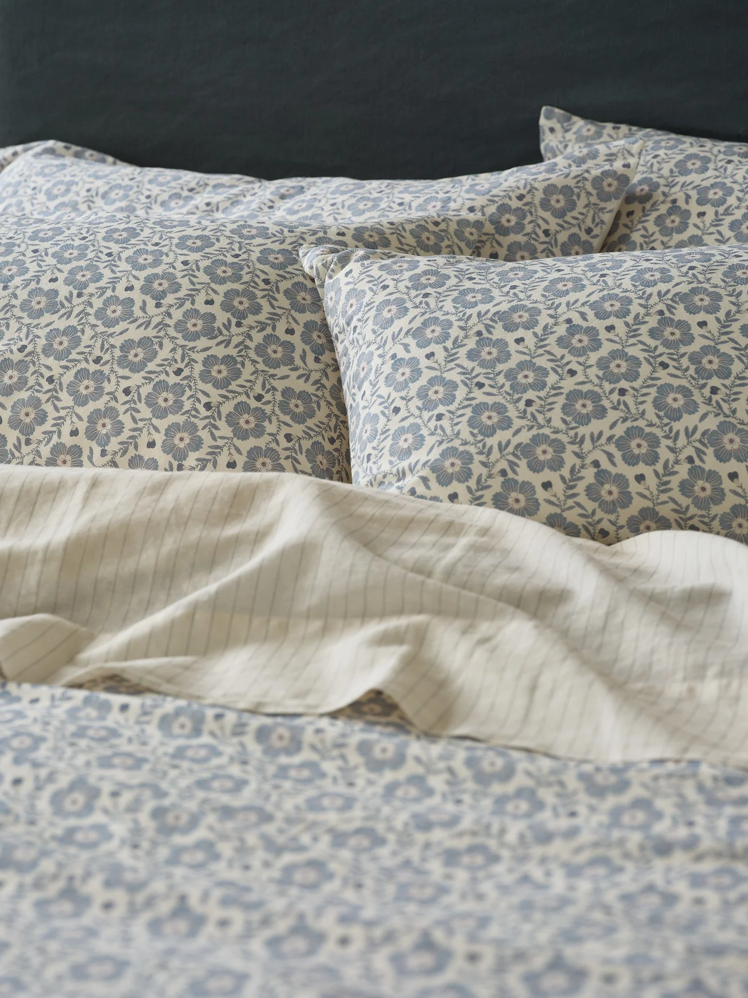 Close-up of layered bedsheets and pillows with floral patterned fabric in shades of blue and white.