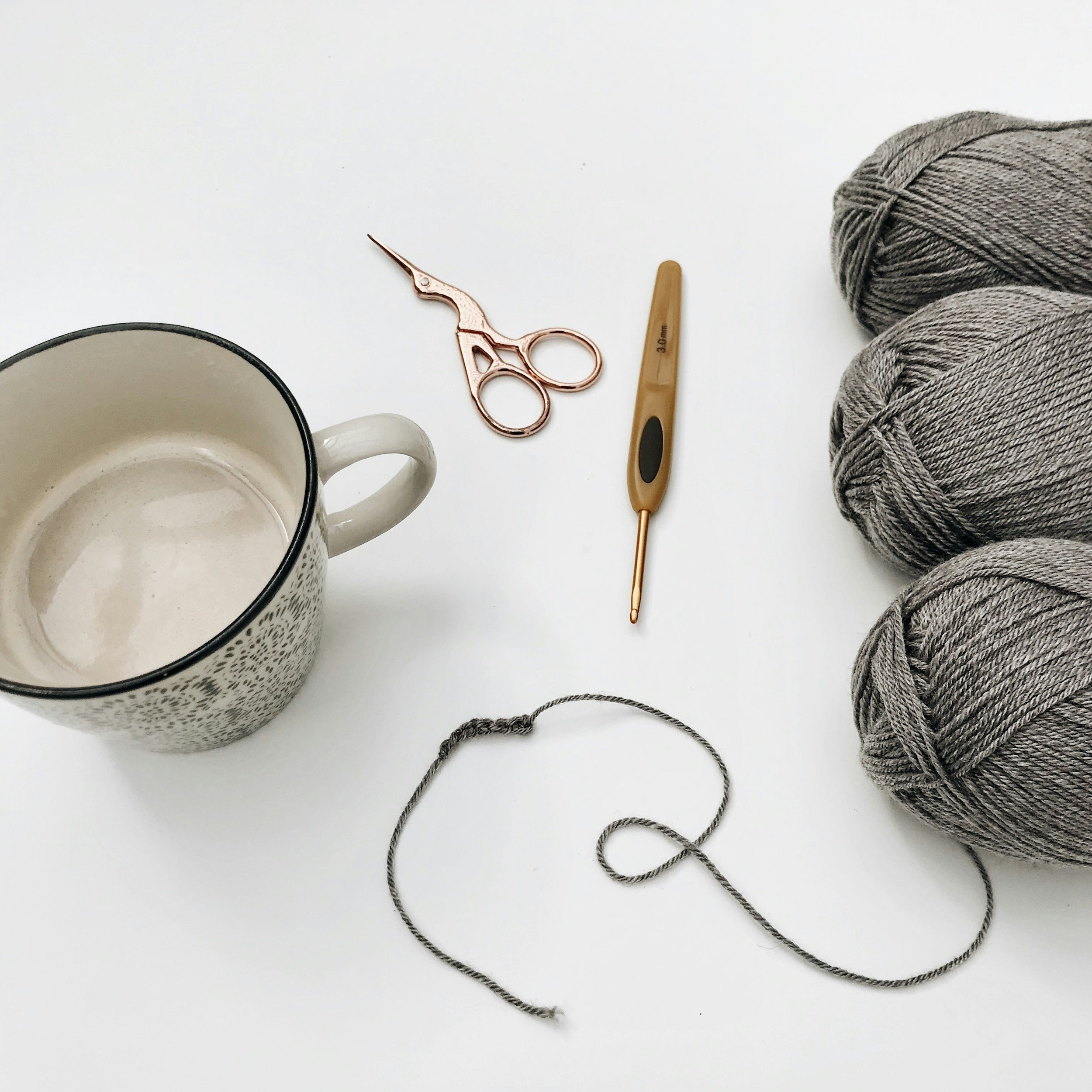 Coffee cup, scissors, hook, and yarn