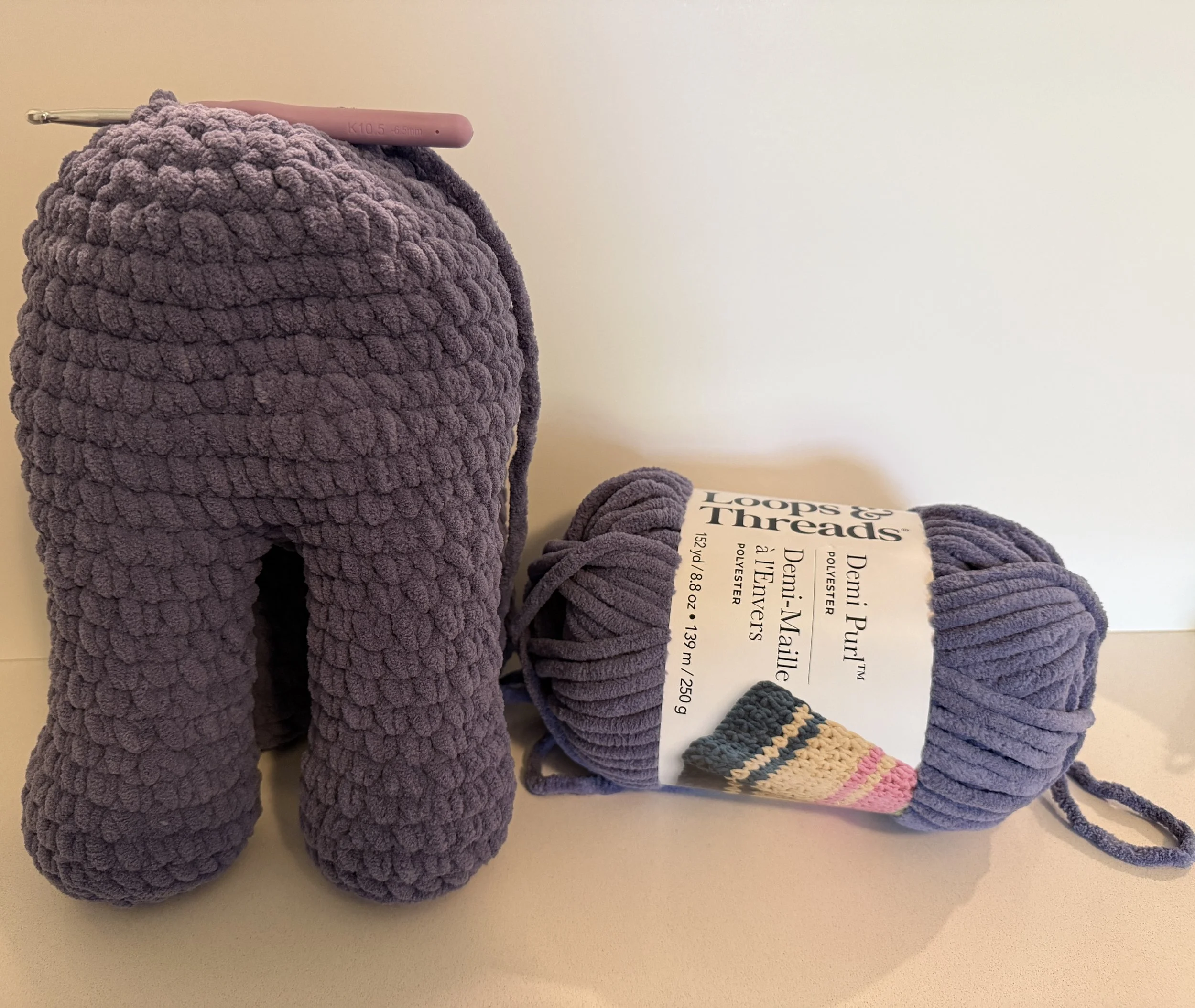 Crocheted elephant body with a skein of yarn.