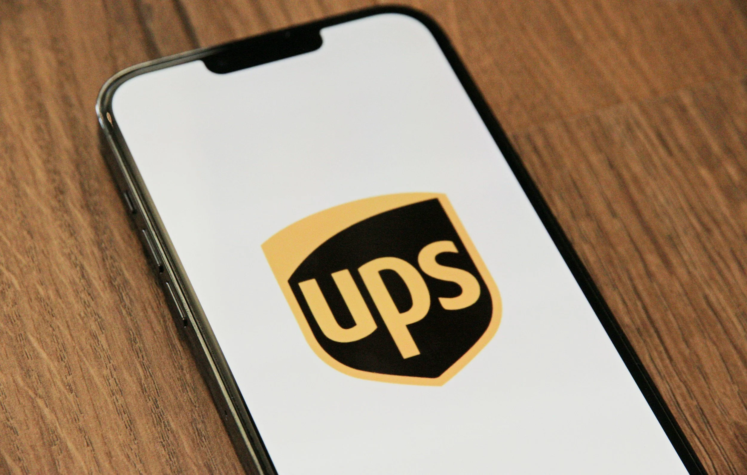 A smartphone showing the Uber logo on its screen, placed on a wooden surface.