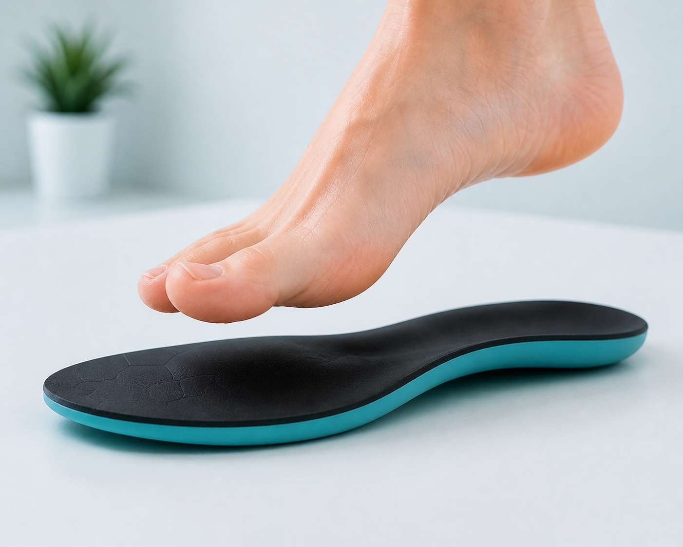 A person pressing a black and teal insoles with their finger on a white surface.