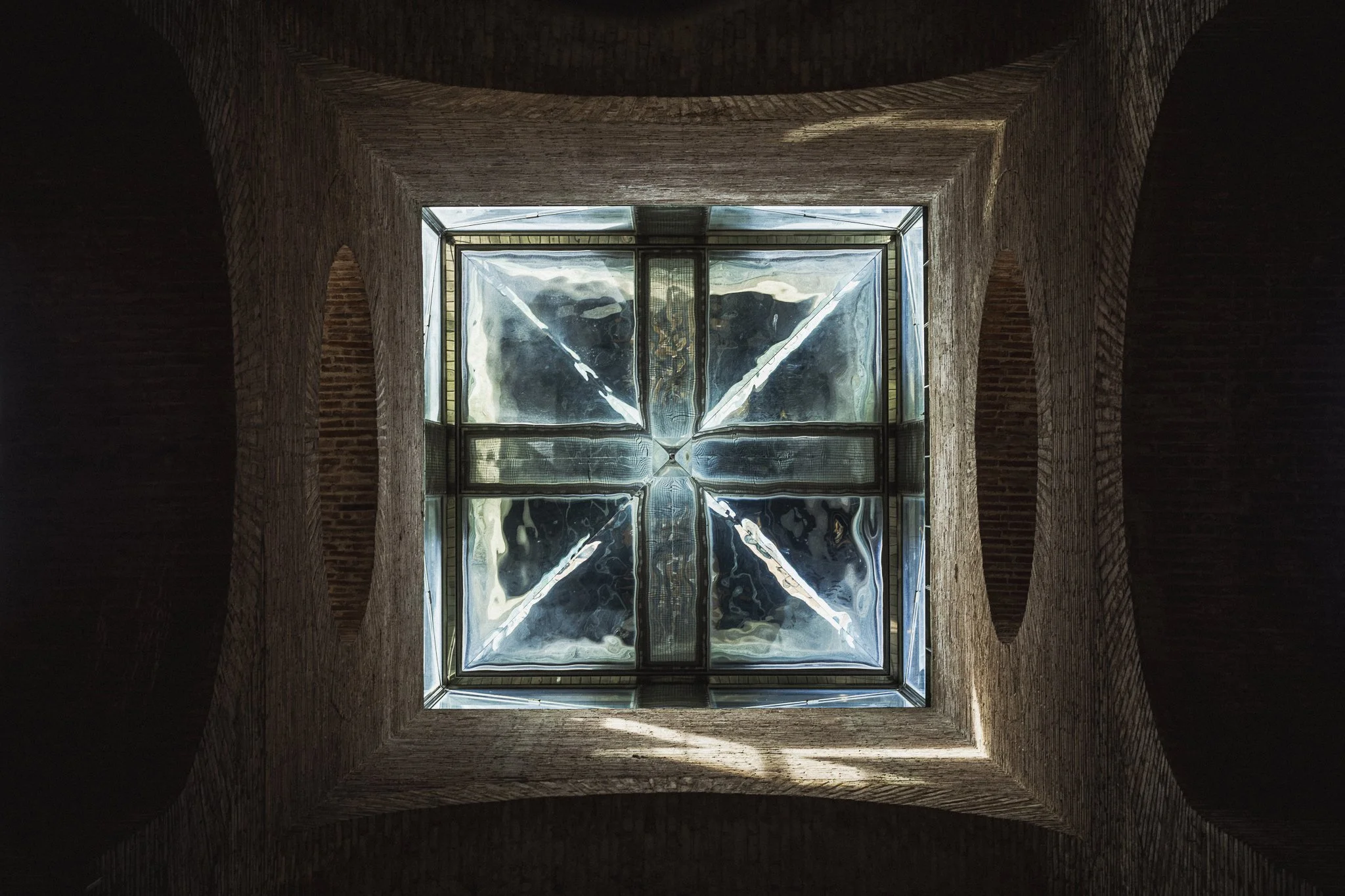 Looking straight up. A square glass skylight set into the brick ceiling
