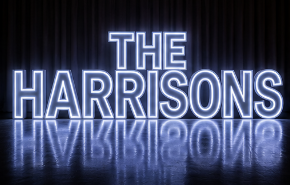 Neon sign reading 'The Harrisons' against dark curtains, with reflection on the floor.