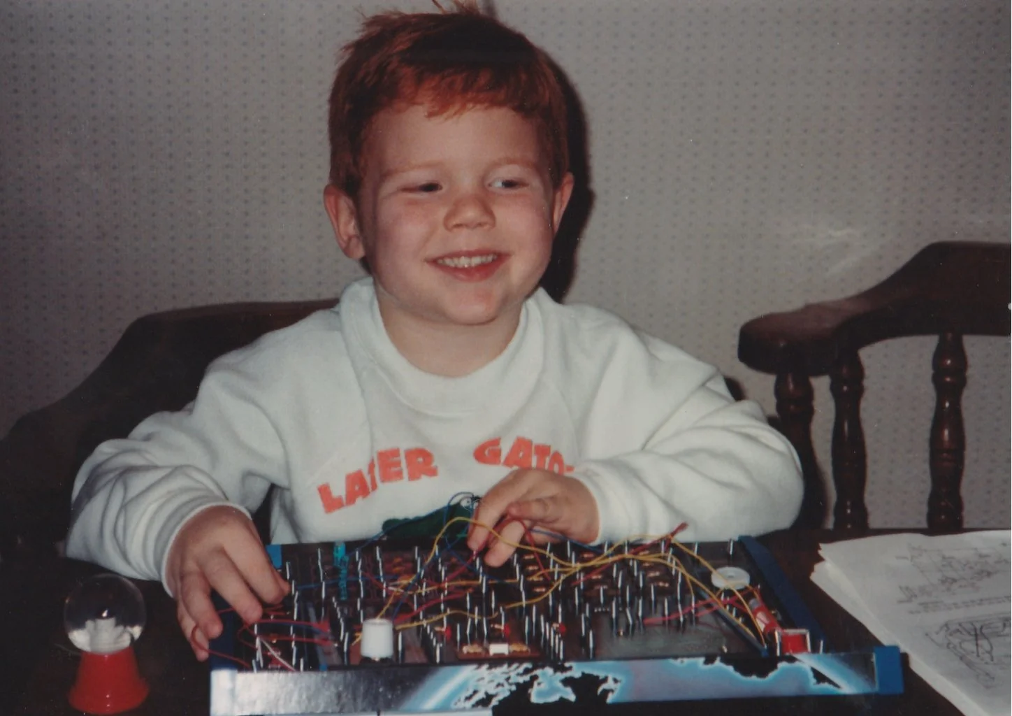 A young redhead boy works on a electronics project kit from Radio Shack on his birthday in 1990. That kid is me, Eddie, the owner of Obsidian Technology!