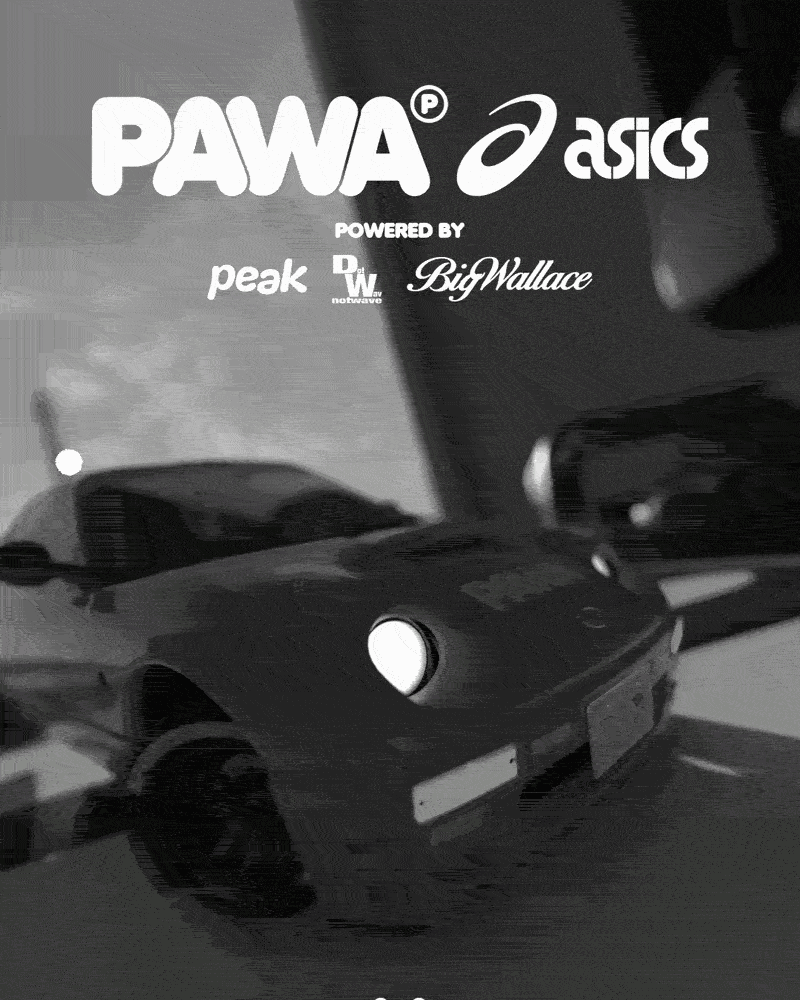 Black motorcycle parked in a garage with logos of Pawa, ASICS, Peak, Big Wallace, and others on the wall in the background.
