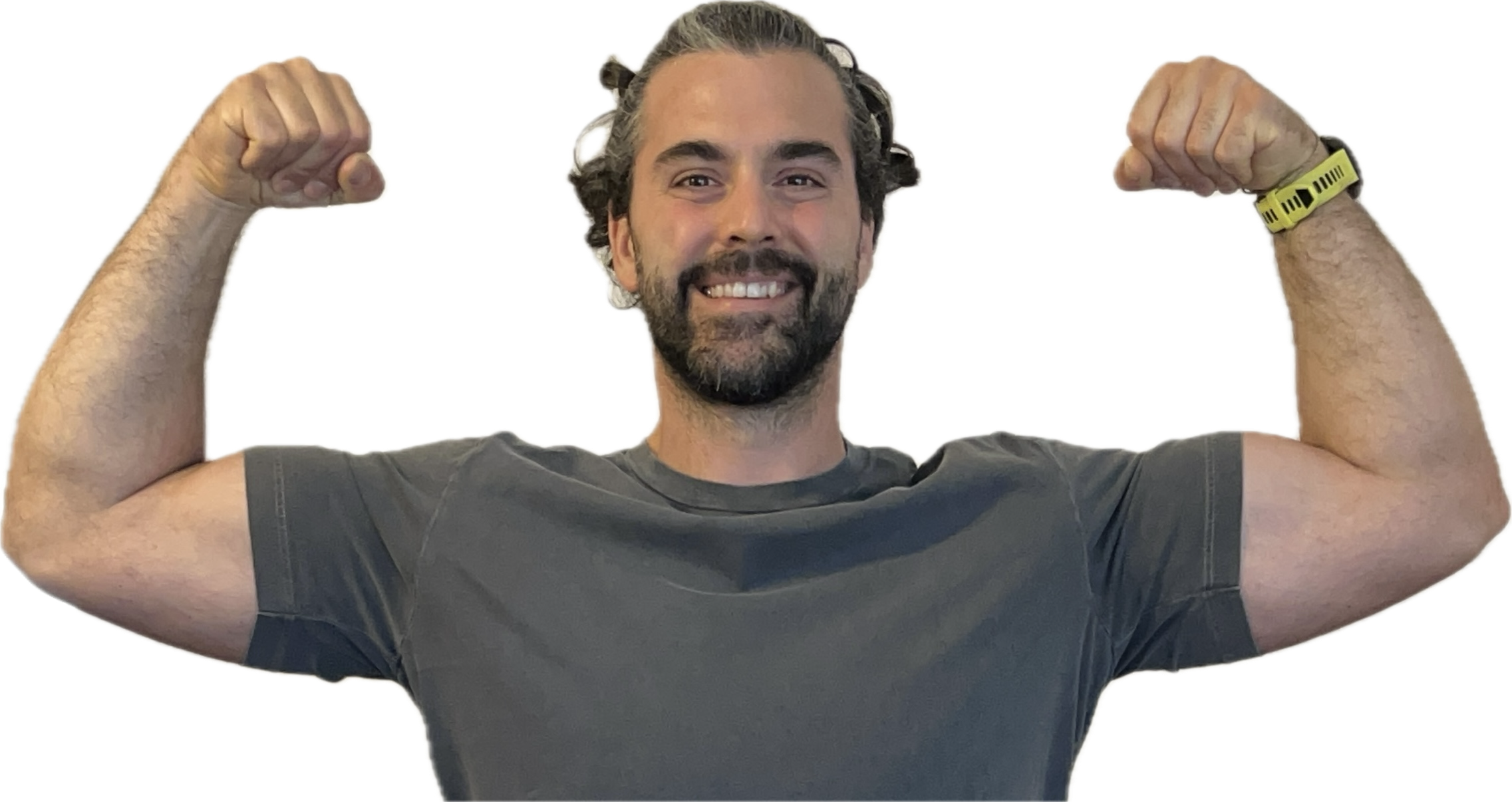 Uomo con capelli ricci e barba, che sorride e mostra i muscoli, indossa una maglietta grigia e un orologio sportivo giallo, posando con i bracci sollevati e i pugni chiusi in segno di forza.