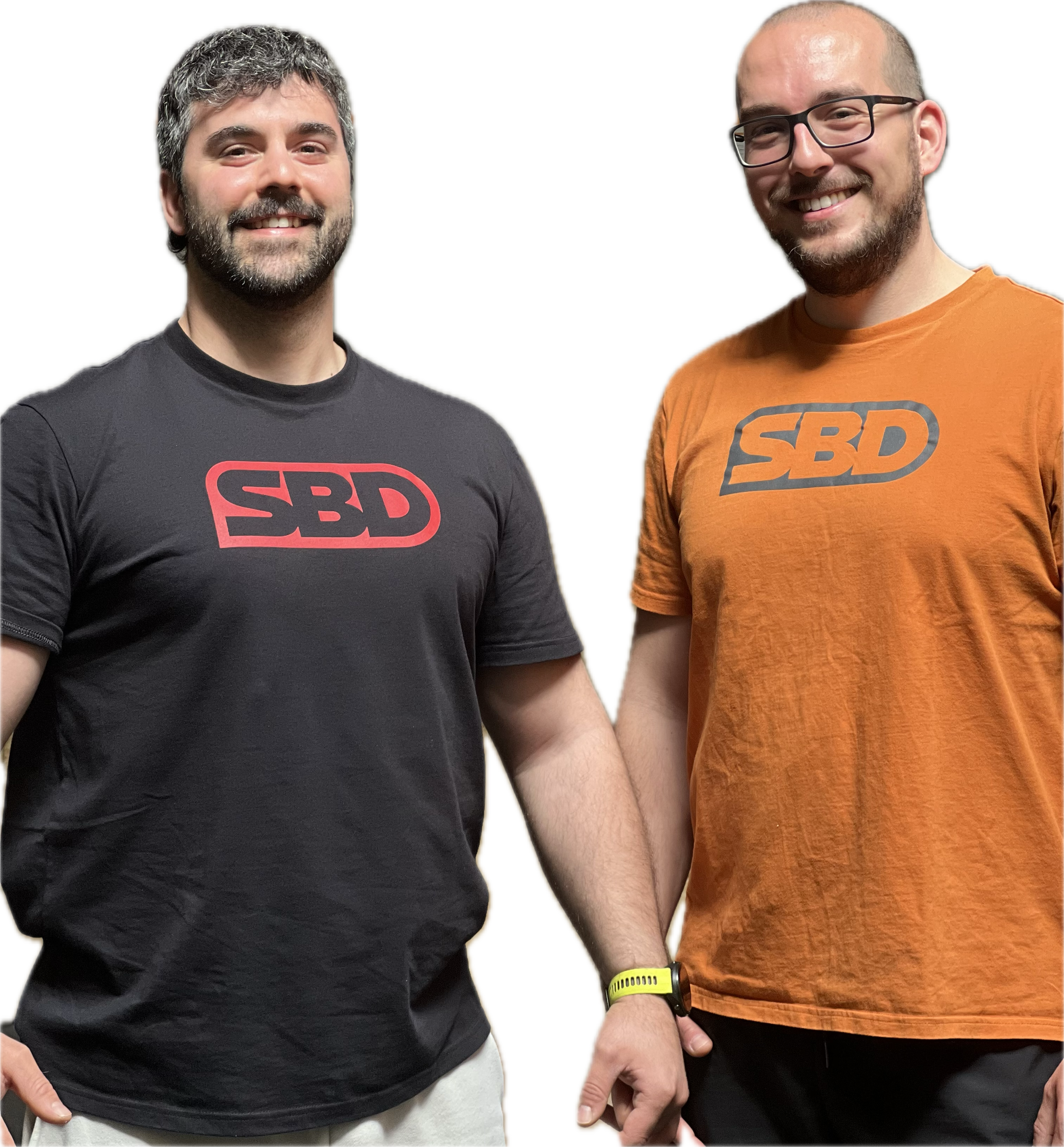 Due uomini sorridenti si tengono per mano, indossano magliette con il logo 'SBD', uno in maglietta nera e l'altro in arancione, con braccia raccolte e mani intrecciate.