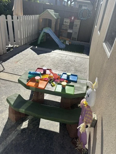 Outdoor daycare playground with playhouse, activity toys, and learning play area