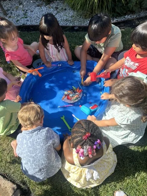 Preschool children working together to rescue toy dinosaurs trapped in ice during a hands on sensory learning activity at BabeeShark Preschool in Sacramento