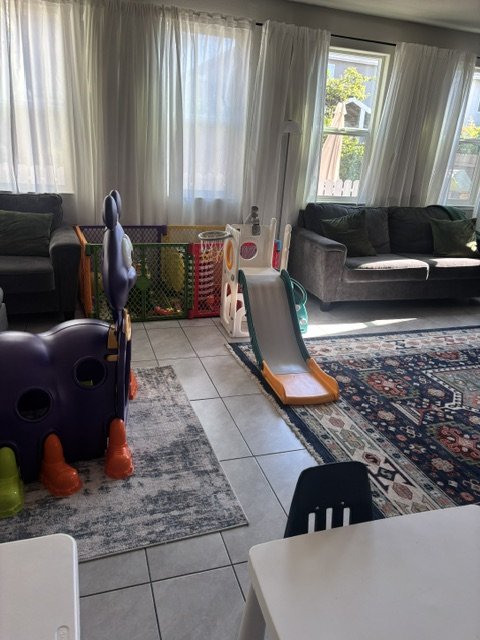 Bright indoor daycare playroom with toys, learning stations, and child-friendly activity areas