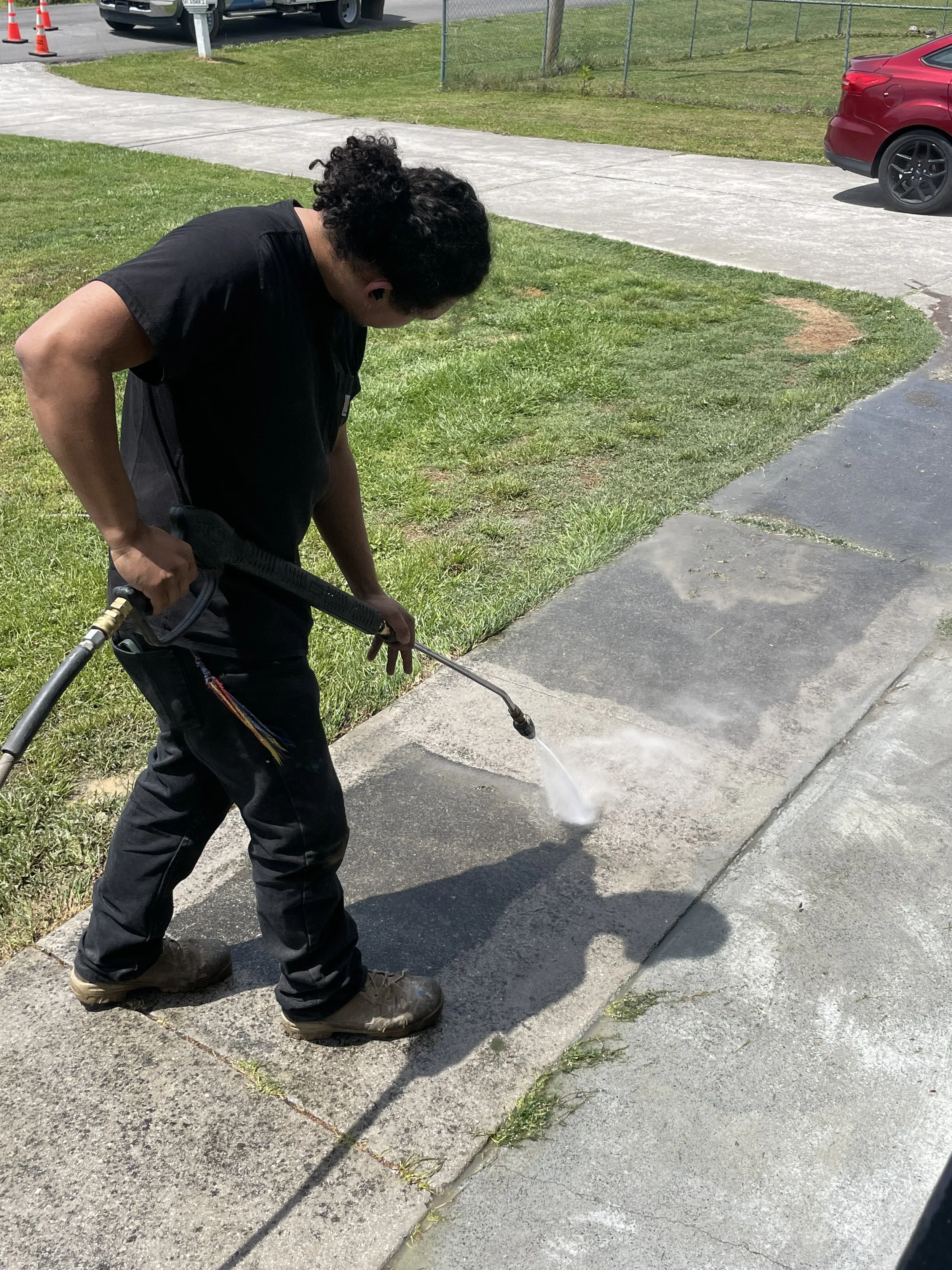 A worker pressure washing a concrete sidewalk outside on a sunny day, pressure washing in Dalton GA