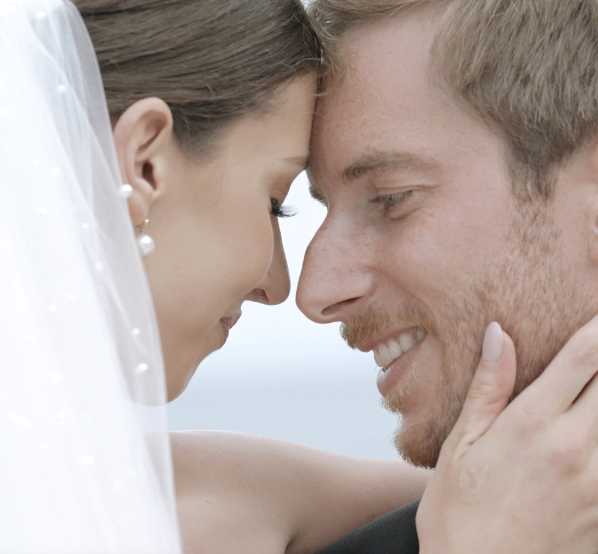 Wedding Videography - Close-up of a woman and a man with foreheads touching and eyes closed, sharing an intimate moment.