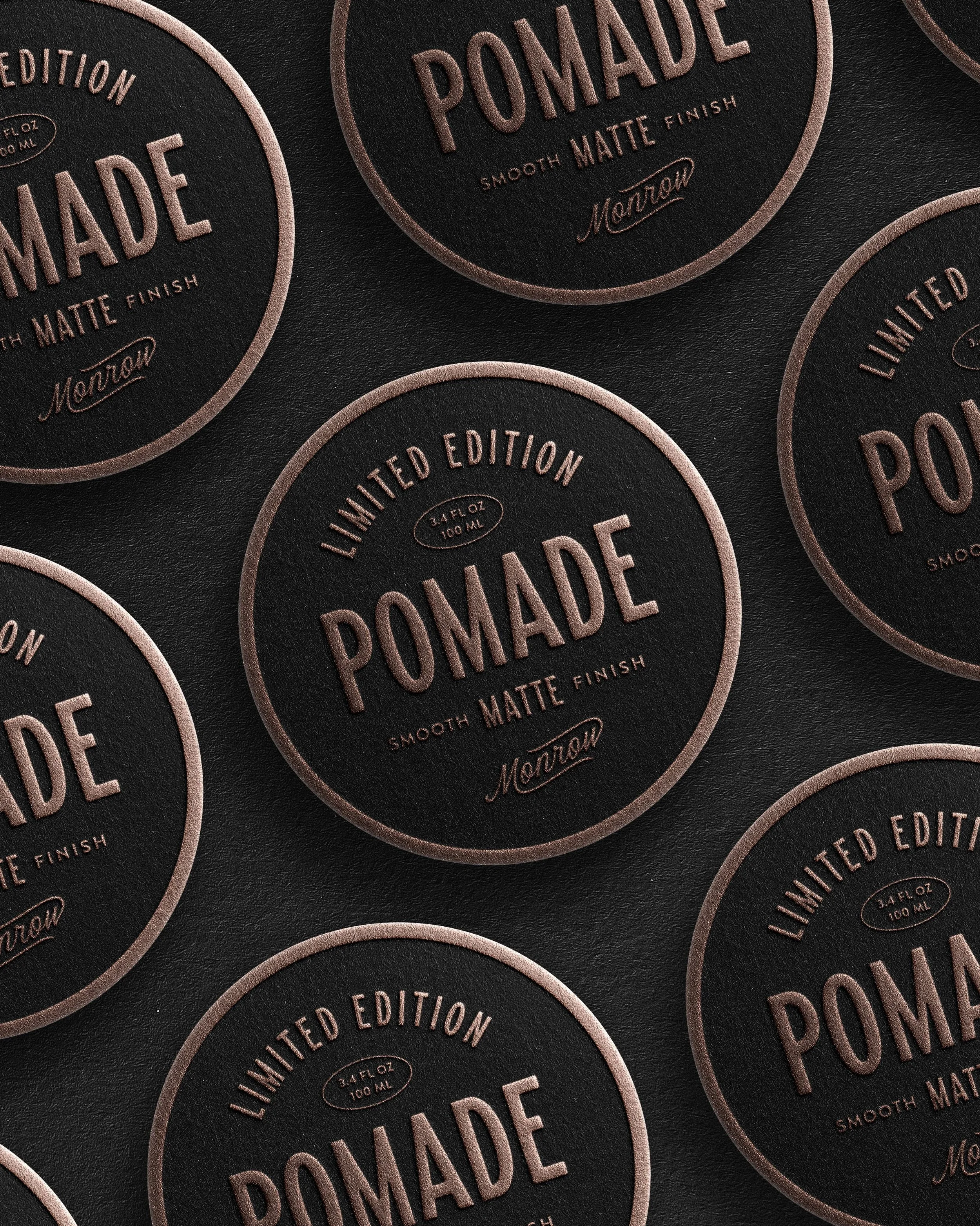 Close-up of black circular labels with a pink border reading 'Limited Edition Pomade Smooth Matte Finish' in raised pink lettering, with the brand name 'Marlow' in cursive.