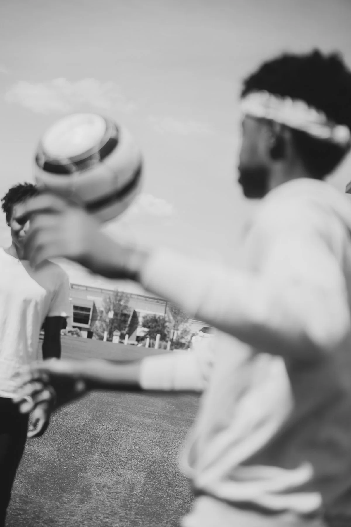 Blurred black and white photo of children outdoors, one child holding a ball, wearing a headband.
