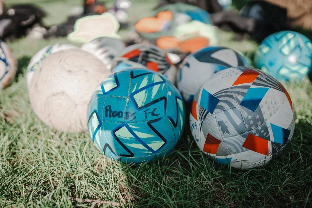 A collection of colorful soccer balls and sports equipment on grass.
