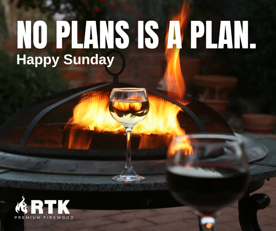 A wine glass and a beer glass in front of a fireplace with flames, outdoor setting, happy Sunday message.