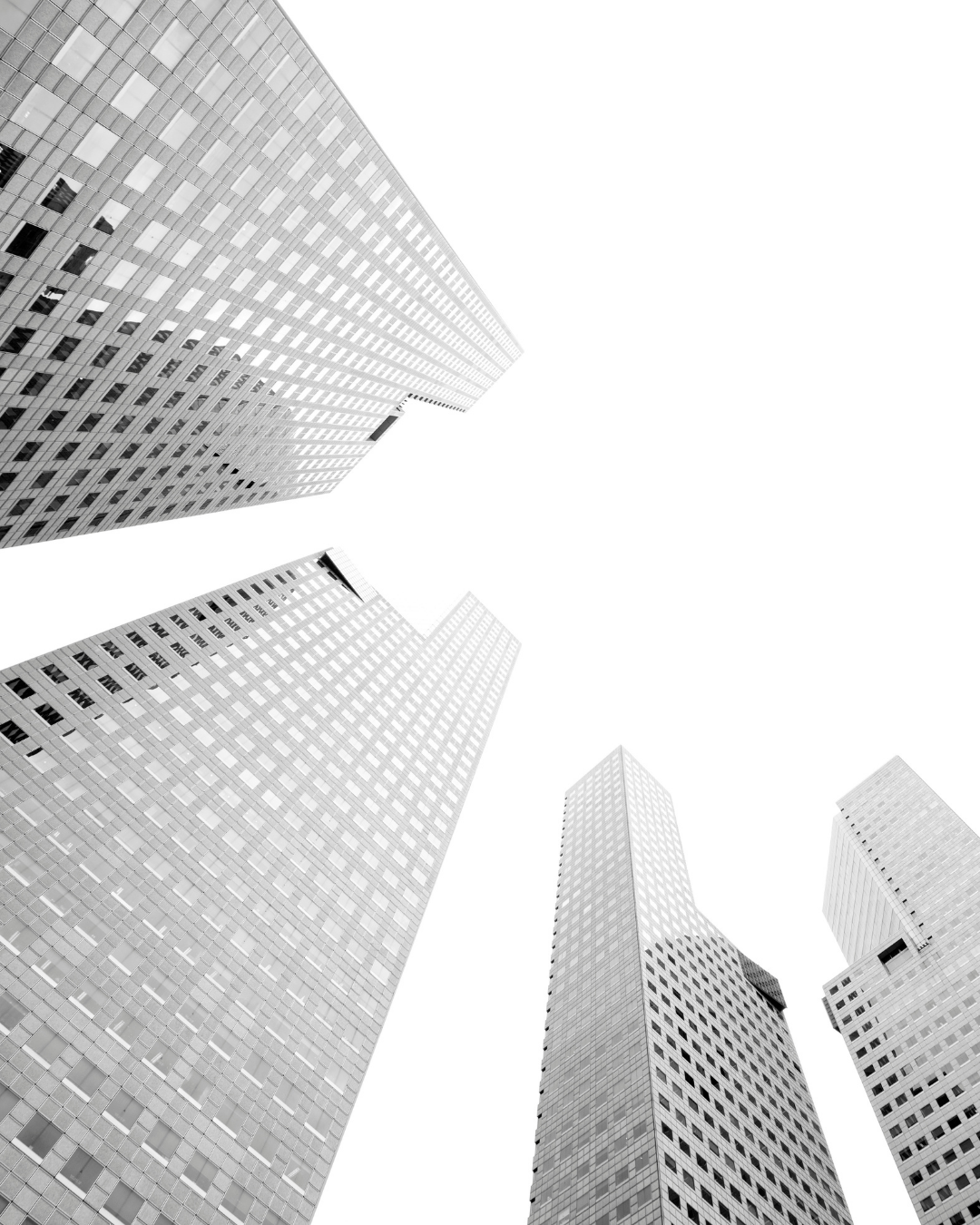 Black and white photograph of tall skyscrapers viewed from the ground looking up.