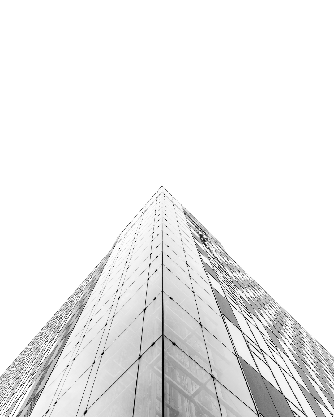 Black-and-white photo of a modern skyscraper viewed from the ground, looking up towards the sky.